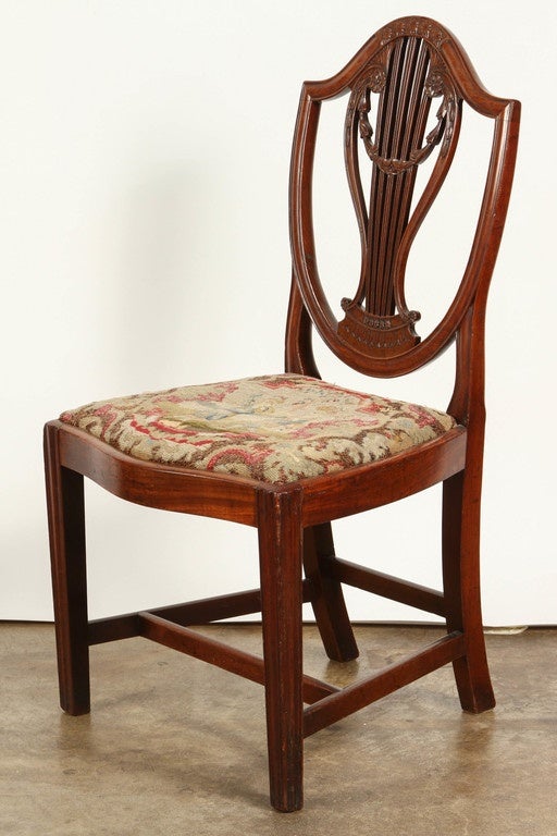 A very important pair of early 18th Century Georgian chairs, in mahogany with period brocade upholstery. The legs on these late 18th century chairs are simple and straight. The lines of the back are gently curved and decorated with florets, a lyre