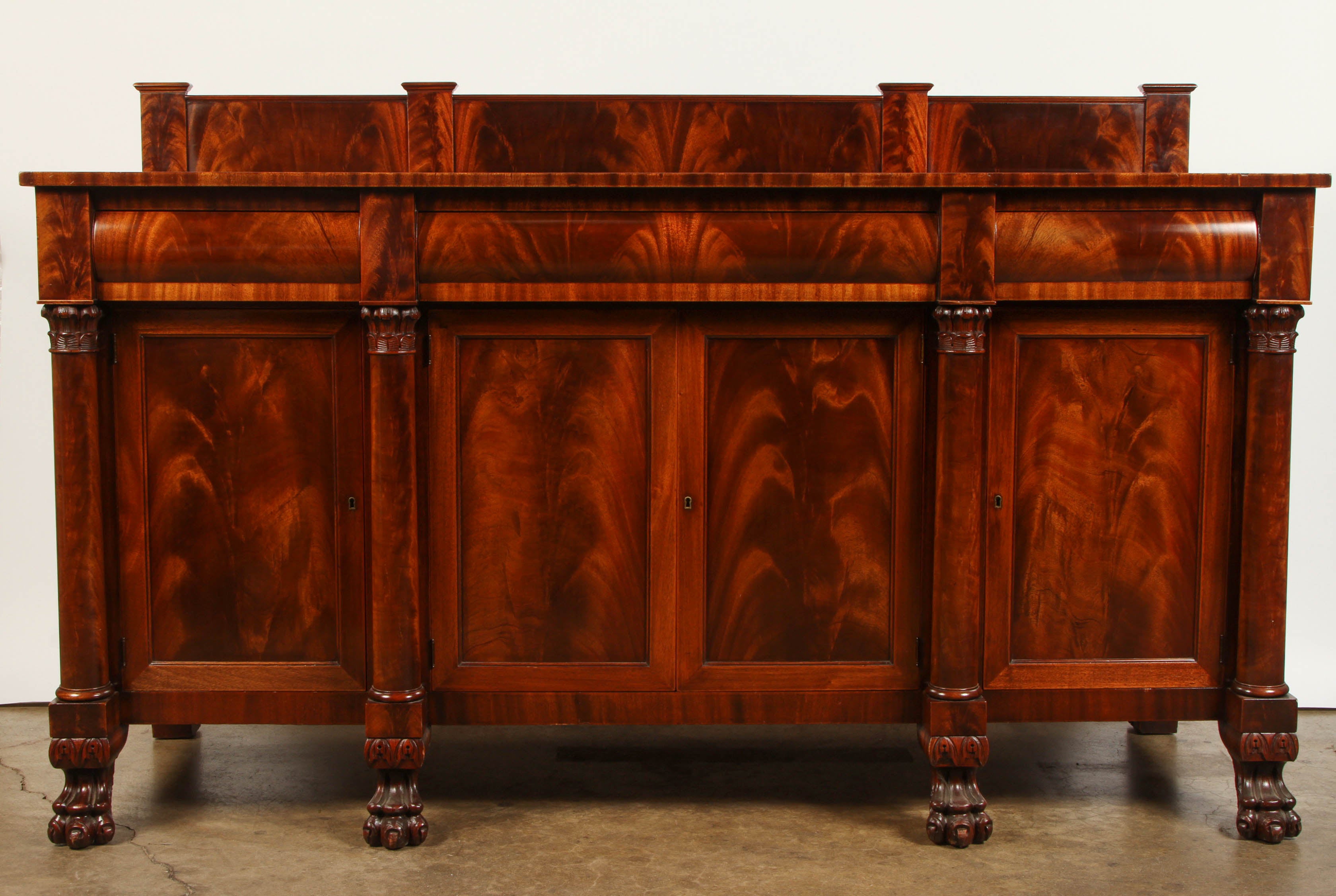 An American Crotch Mahogany sideboard, manufactured by Hathaway.  The sideboard has full columns with plinths and capitals, carved lion's foot supports, with a maker's plaque. The name is W.A. Hathaway, NY, NY. The center portion has 4 shelves, with