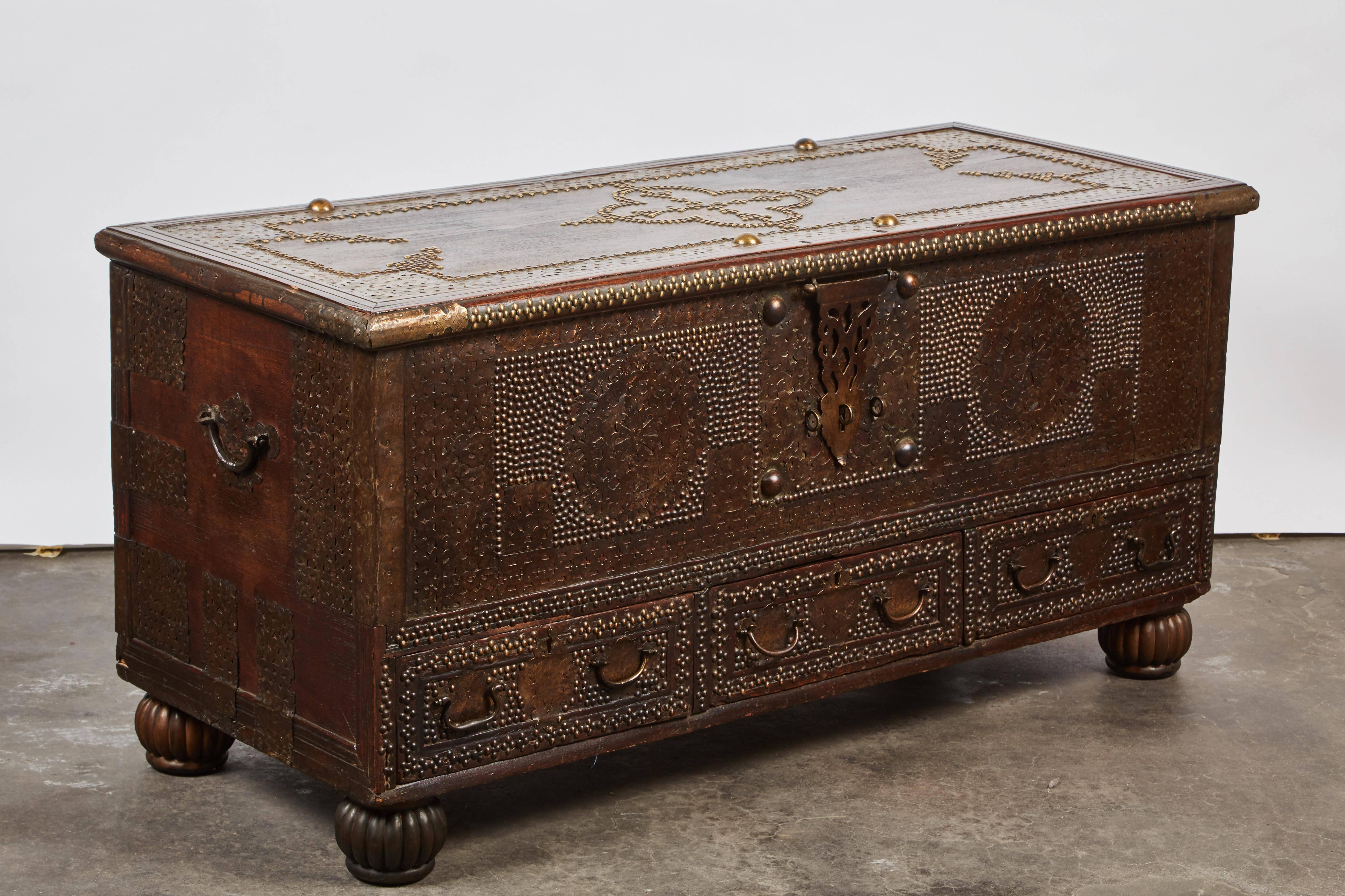 19th century brass studded Indian teak trunk, elaborately decorated with brass nailheads and handles. Three drawers provide extra storage below.