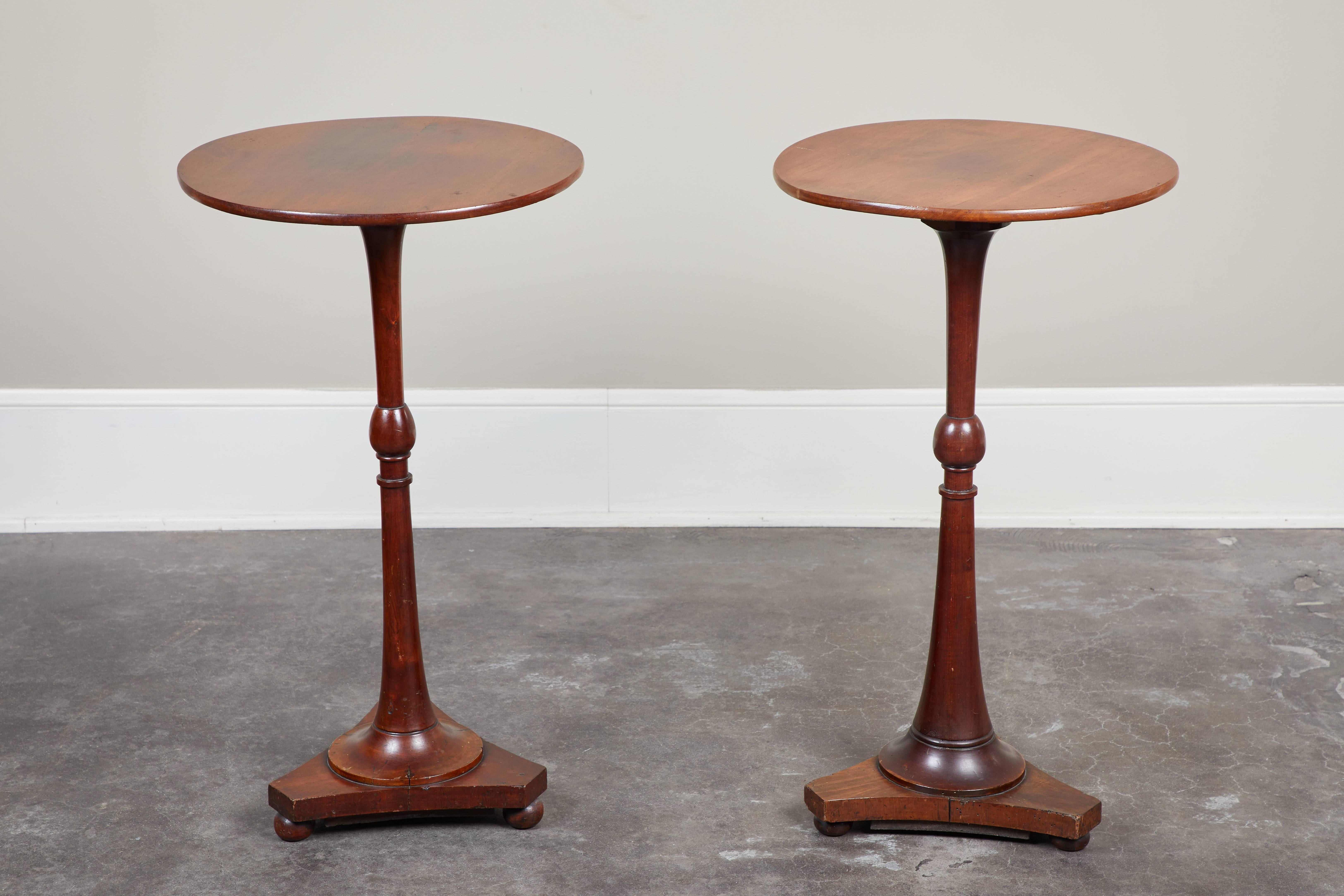 A pair of English Regency Campaign mahogany side tables, circa 1825. Round tabletop on fluted pedestal base with ball feet and single bobbin detail on a turned stem.