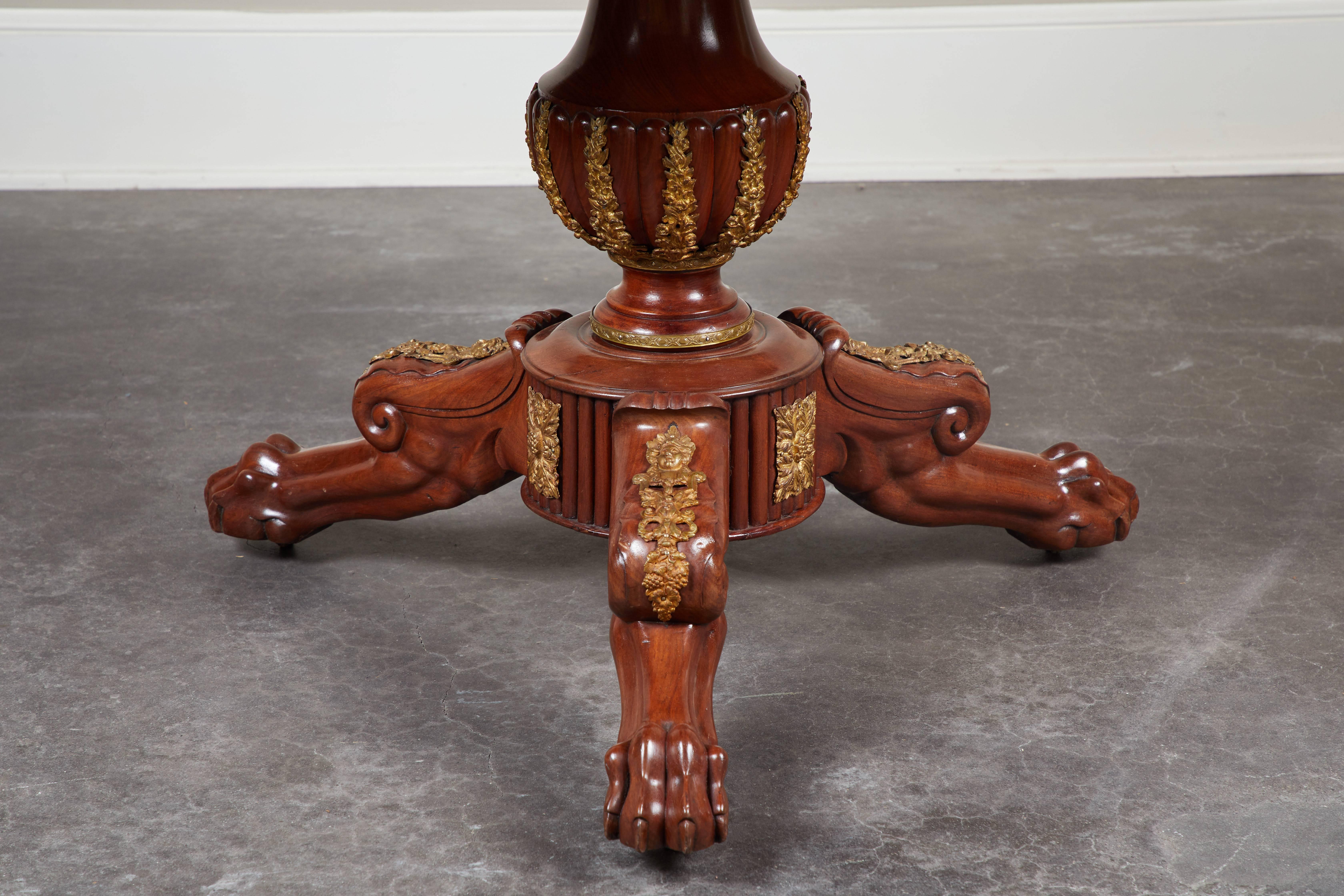 An early 19th century French Empire mahogany pedestal table. Features ormolu details, a black granite top with beveled lip, and urn-shaped base.