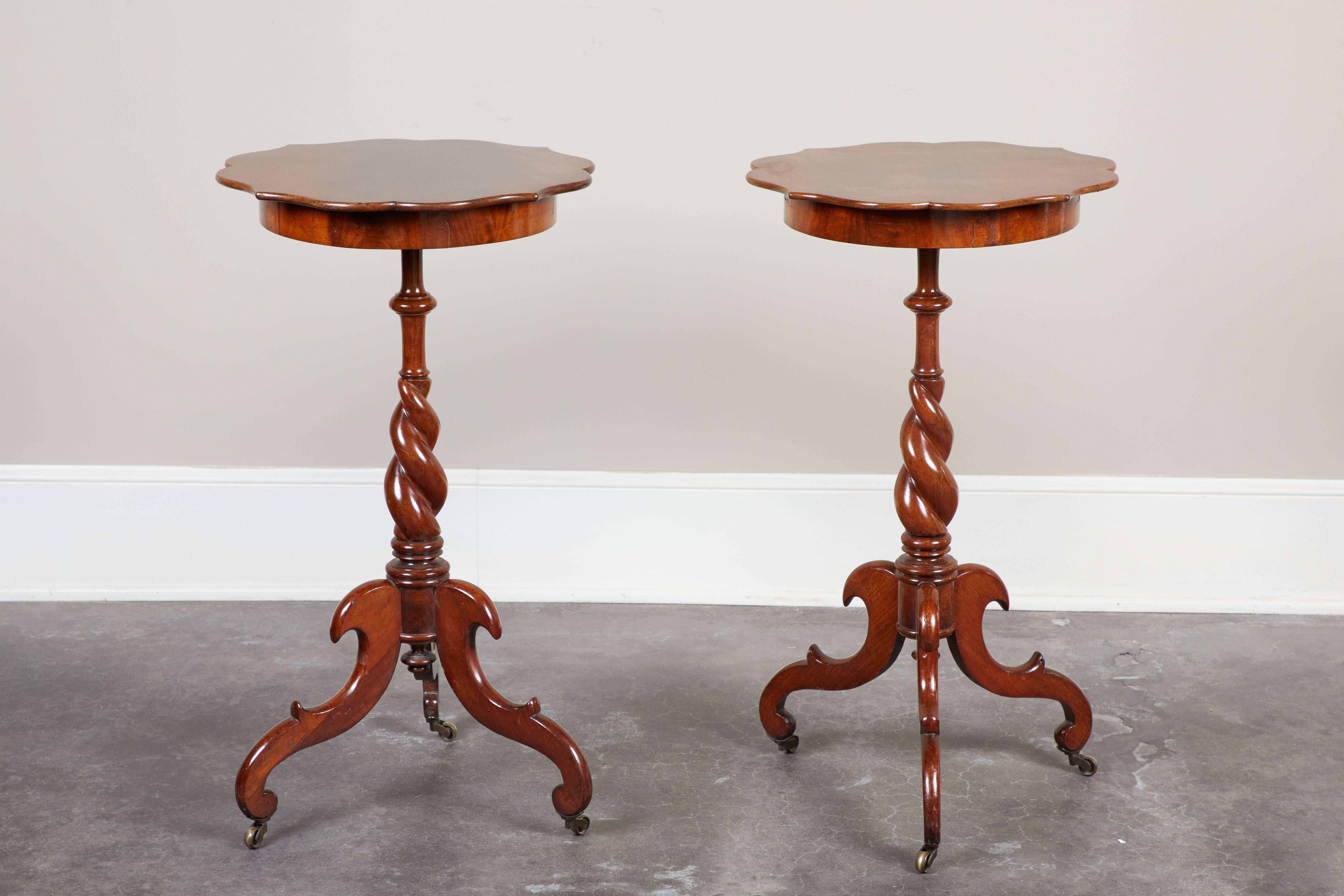 A pair of late 19th century Swedish walnut side tables. Single board top, on intricately carved base on tripod legs with wheels.