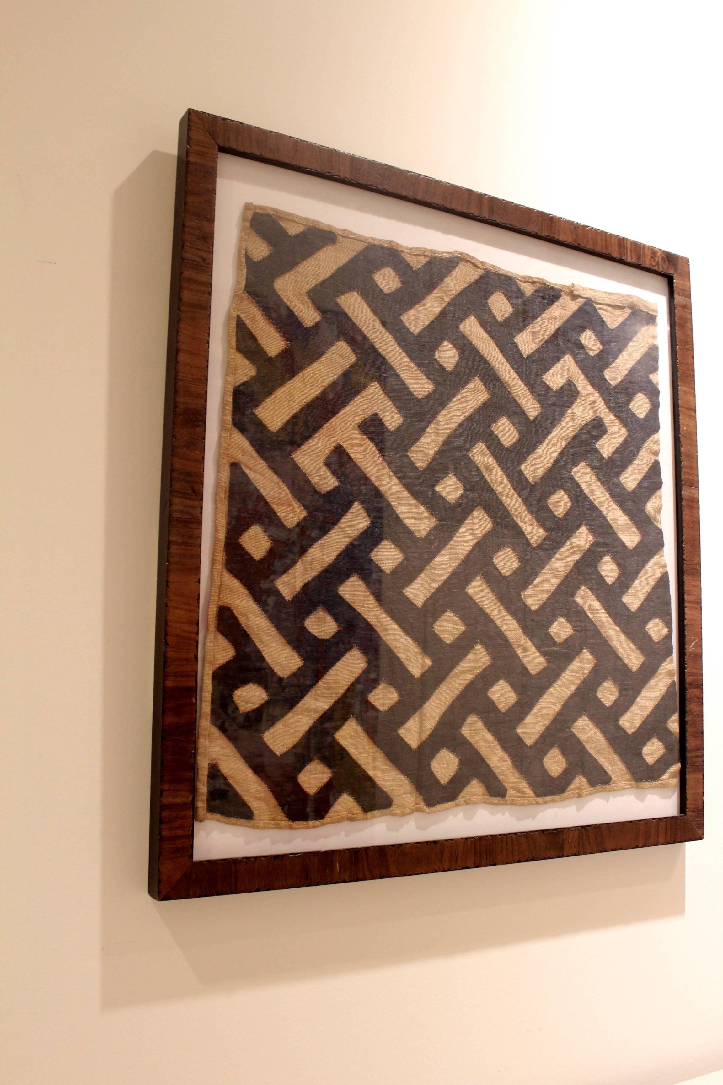 Midcentury Framed African tribal kuba cloth,
 Kuba cloths signify the story making and tribal art of the Congo. Burl walnut frame. 

In Congo culture, the men design and weave the  Kuba cloth, 
made with pieces of  palm leaf fiber. Handwoven
