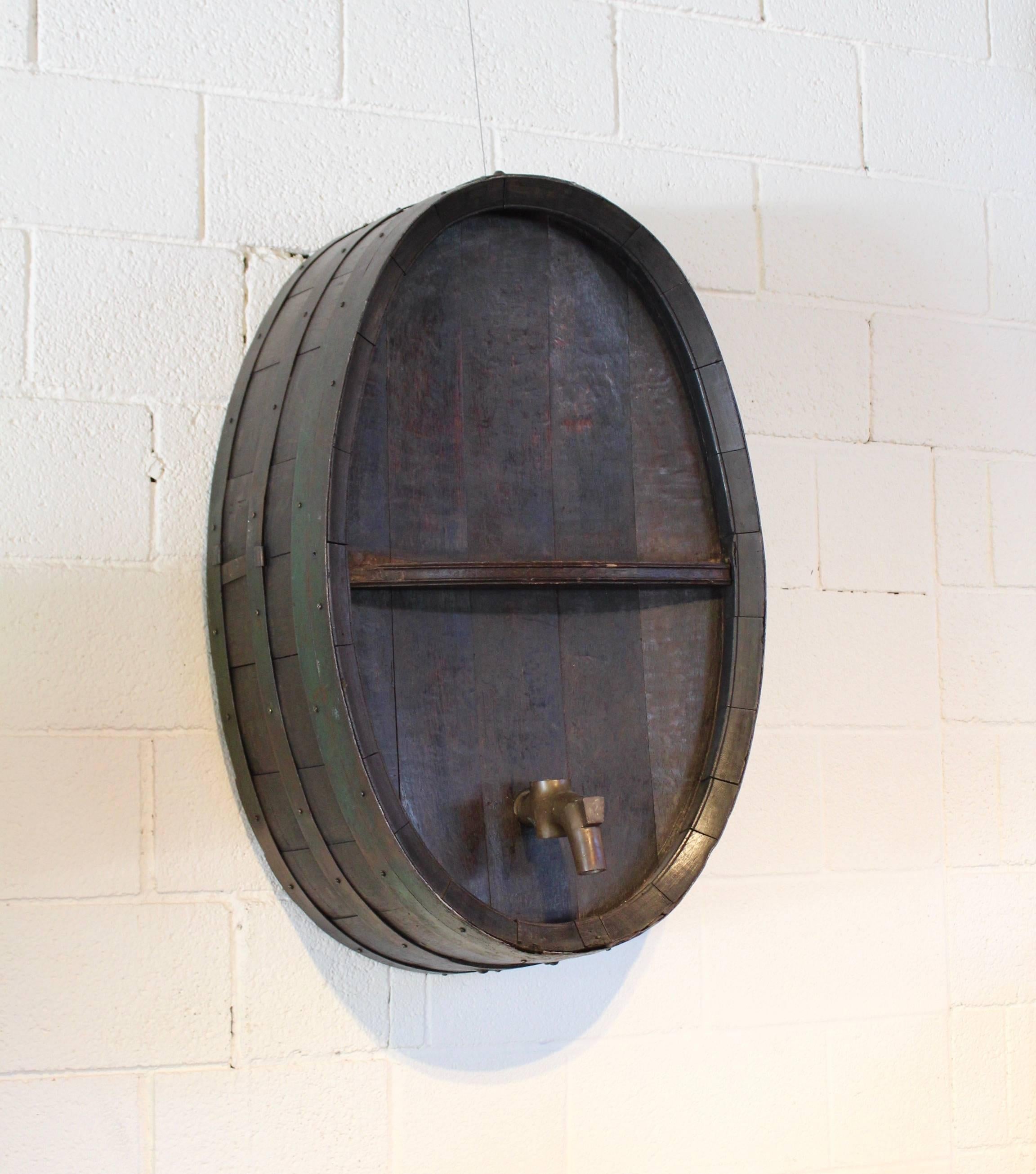 Antique Frenchiron banded green wine barrel as wall decor, circa 1900.
Primitive, iron banded with original green patina wine barrel as wall decor.
Wine barrel comes with brass spout.
Dark wood antique brown natural patina. 
Wine cask face is