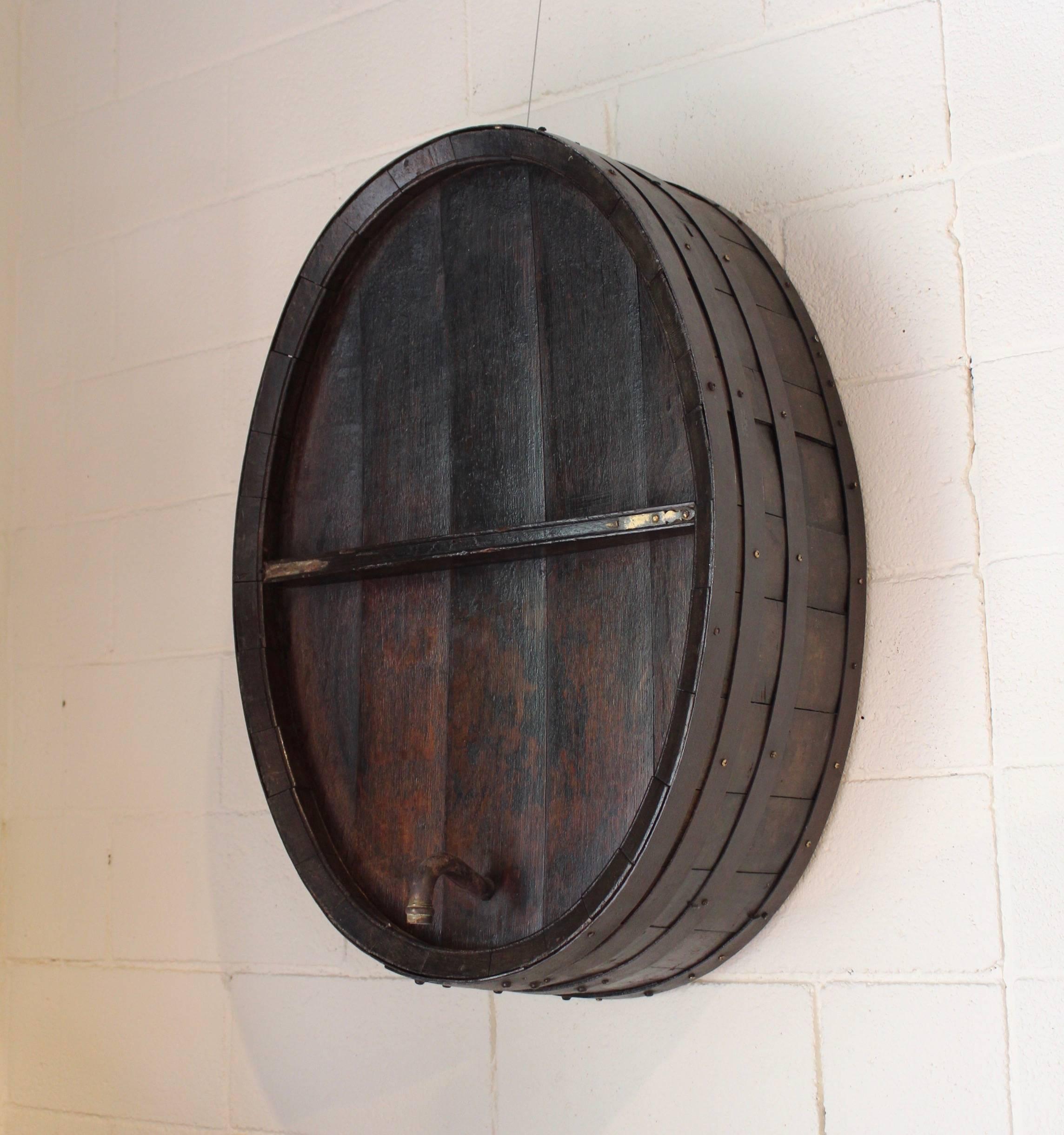 Antique French iron banded wine barrel as wall decor, circa 1900.
Wine barrel comes with brass spout and hardware. 
Dark wood antique brown natural patina. 
Wine cask face is from Normandy, known for their white wines: The wines produced in