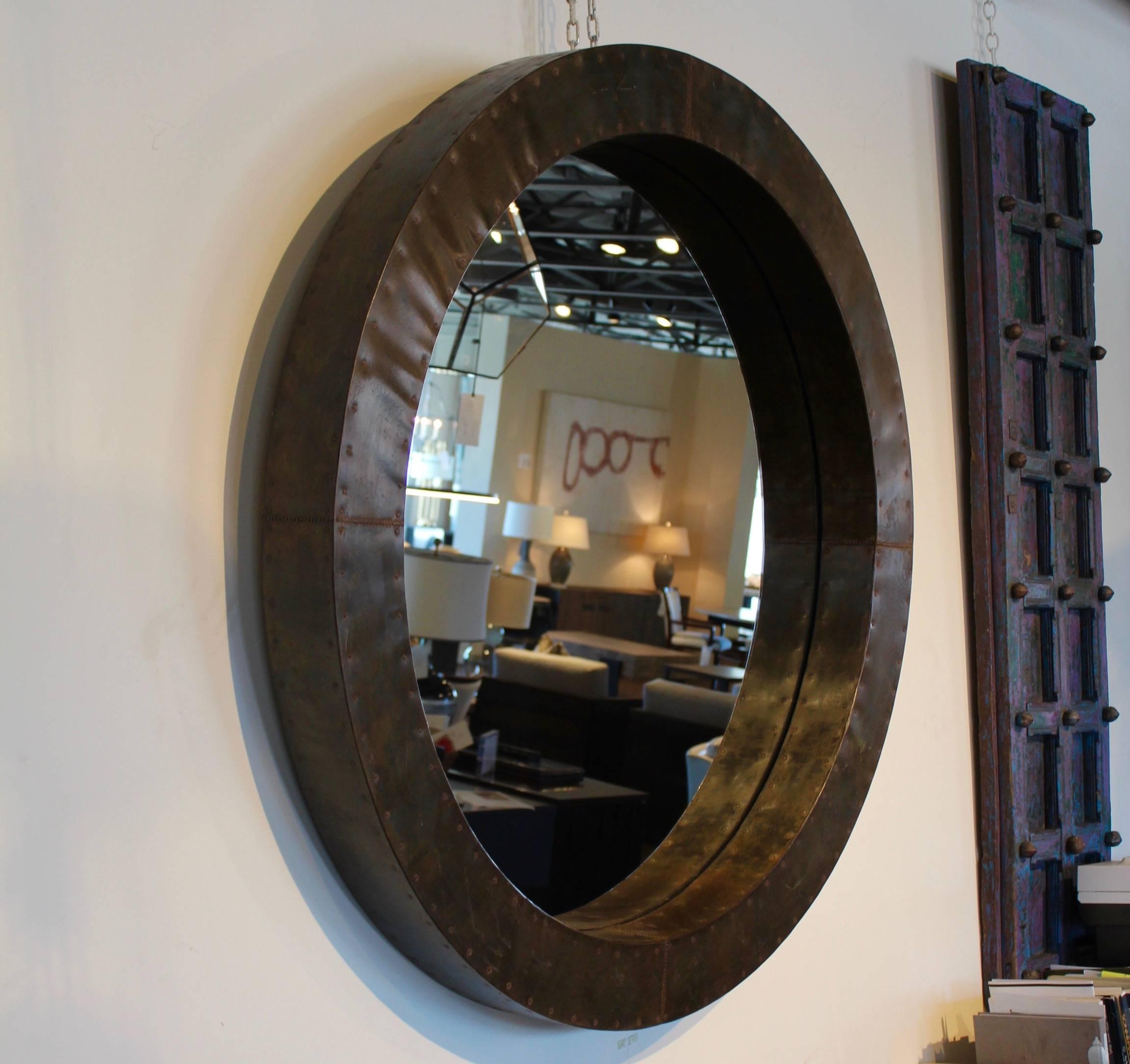 Patinated zinc mirror frame with nailhead accents.