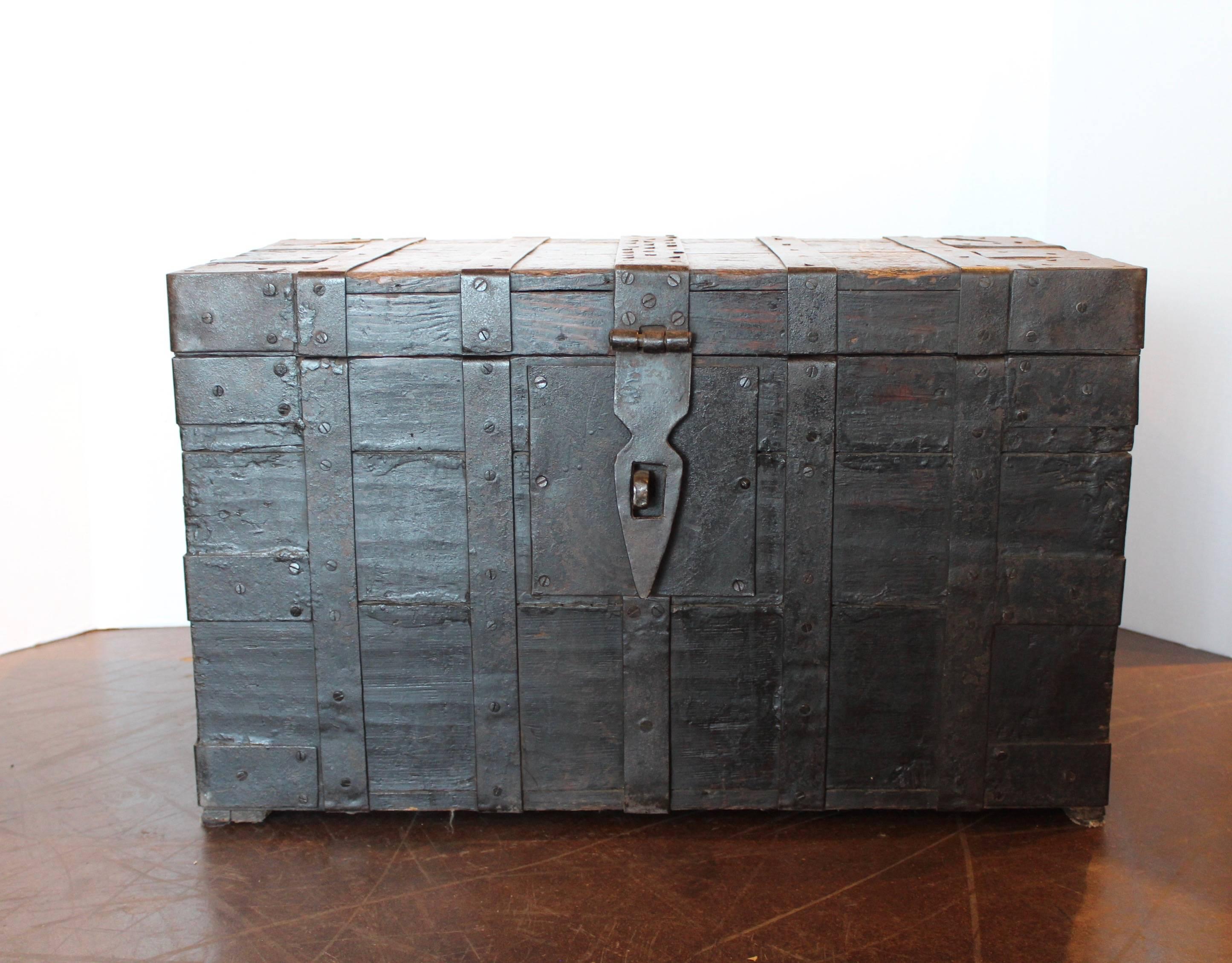 Antique Belgium wood trunk with cast iron, 1890.
Detailed rivet cast iron bolts on patinated steel stripes with dark brown wood.
Cast iron handles on the sides.
Detailed lock hardware in the front.
Storage box space, interior measurements: 14