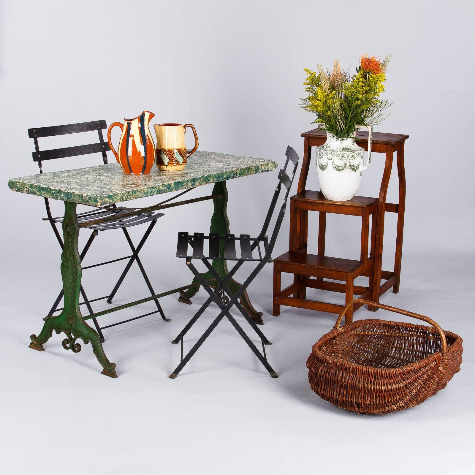 A French green garden table from Provence, late 1800s, featuring a wonderful cast iron base with a dark green aged patina and shaped legs with carved motifs and scrolls. The top is a slab of concrete that was later sponge painted in white and