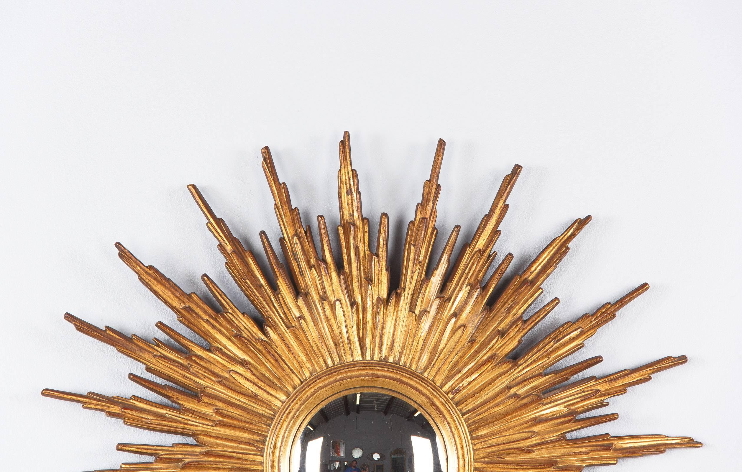 A Sunburst or Starbust mirror from France, circa 1950s with a molded frame made of gilded composite wood. The convex glass measures 7.25