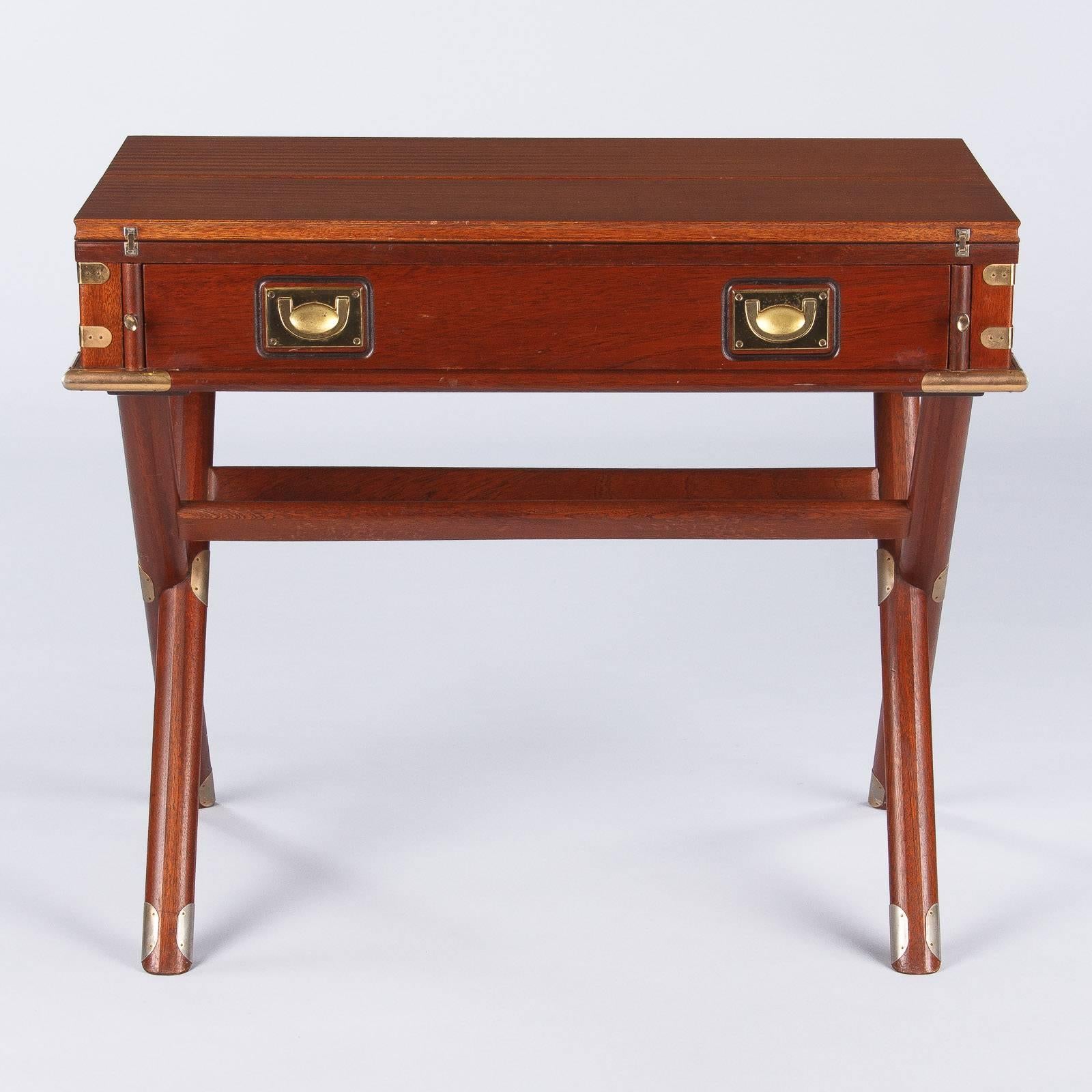 A very interesting and unusual Campaign Style English desk, that can also be used as a console table, made of ribbon mahogany. The desk, circa 1960s, has a nautical style and features two drop leaves that when opened make the piece 37.25