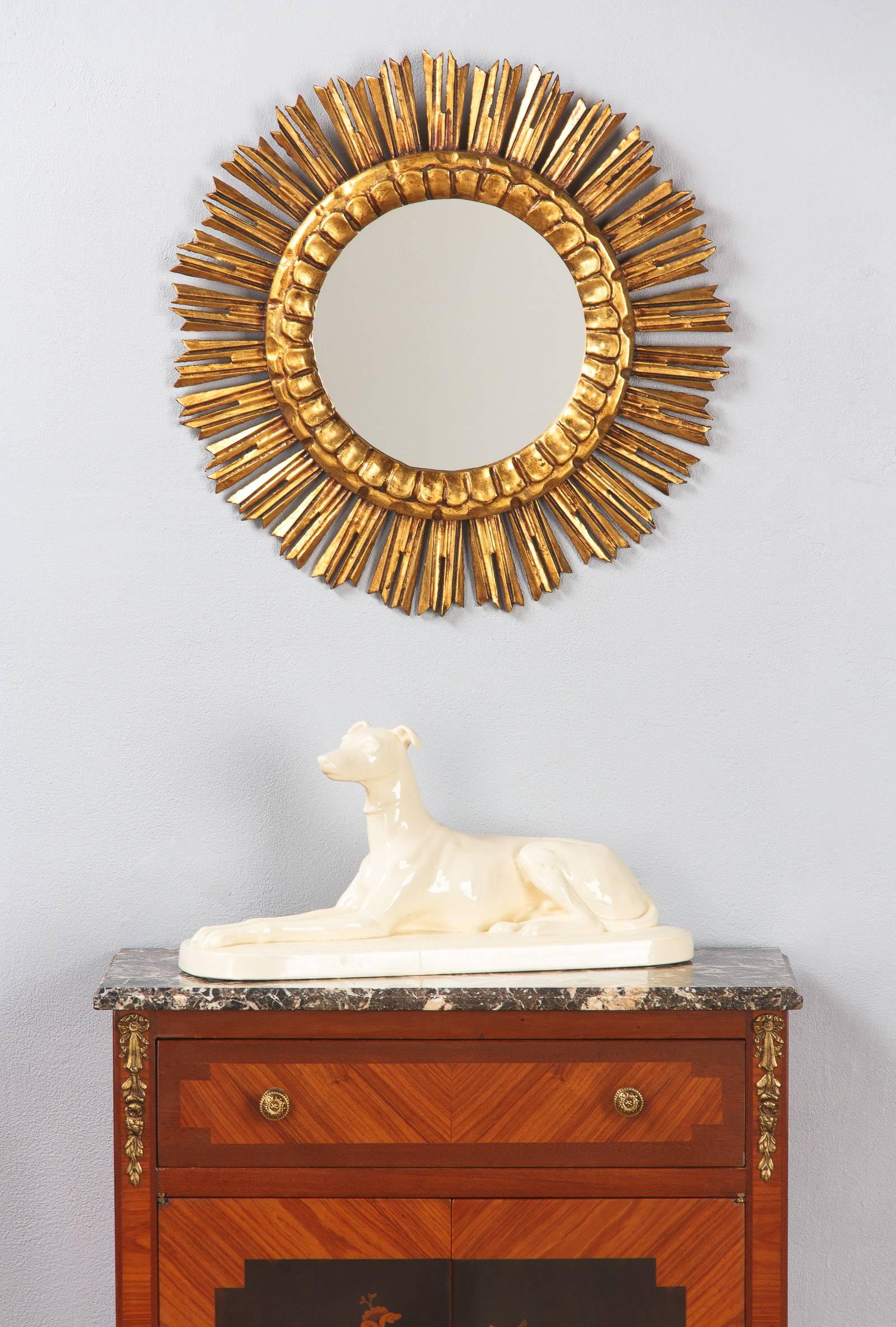 A round sunburst mirror made of giltwood with a nice aged patina. The glass is 9.5