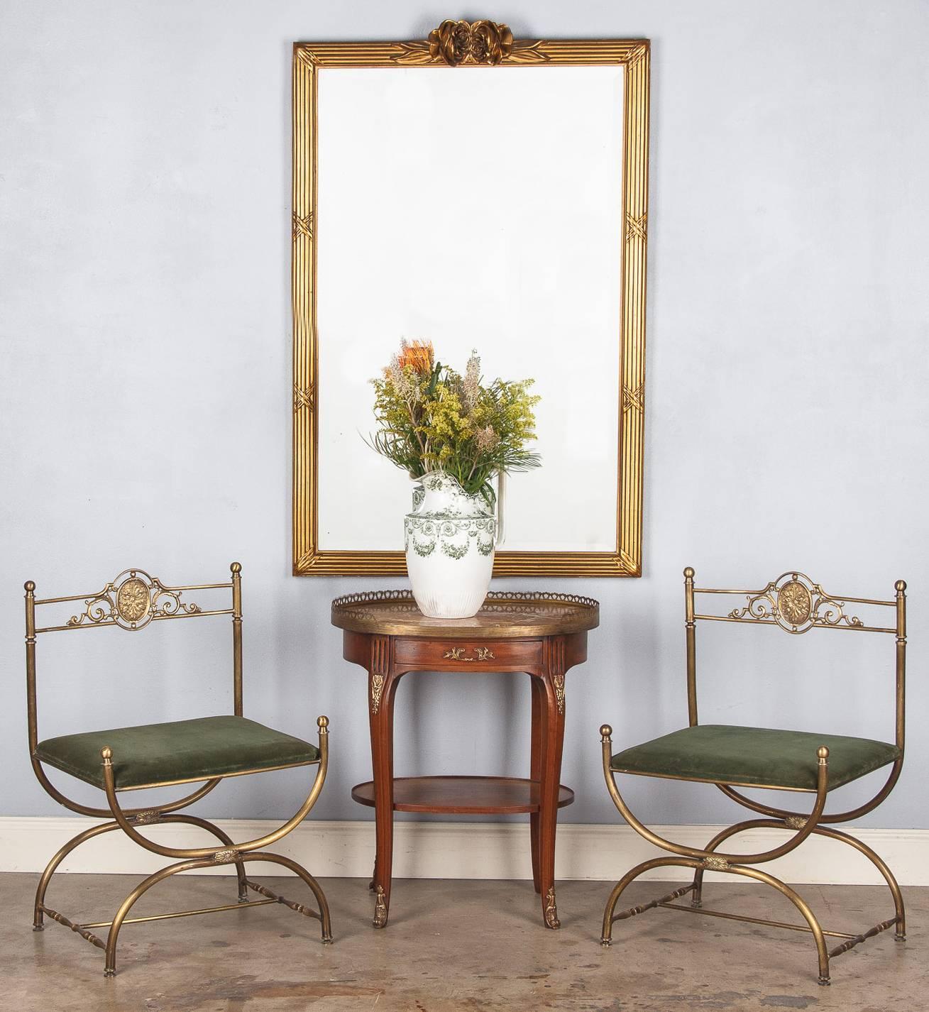 An elegant giltwood mirror in the Louis XVI style that was purchased in the Beaujolais Region. The frame has a fascia molding and cross ribbon motifs with carved roses at the crest. The mirrored glass is beveled.