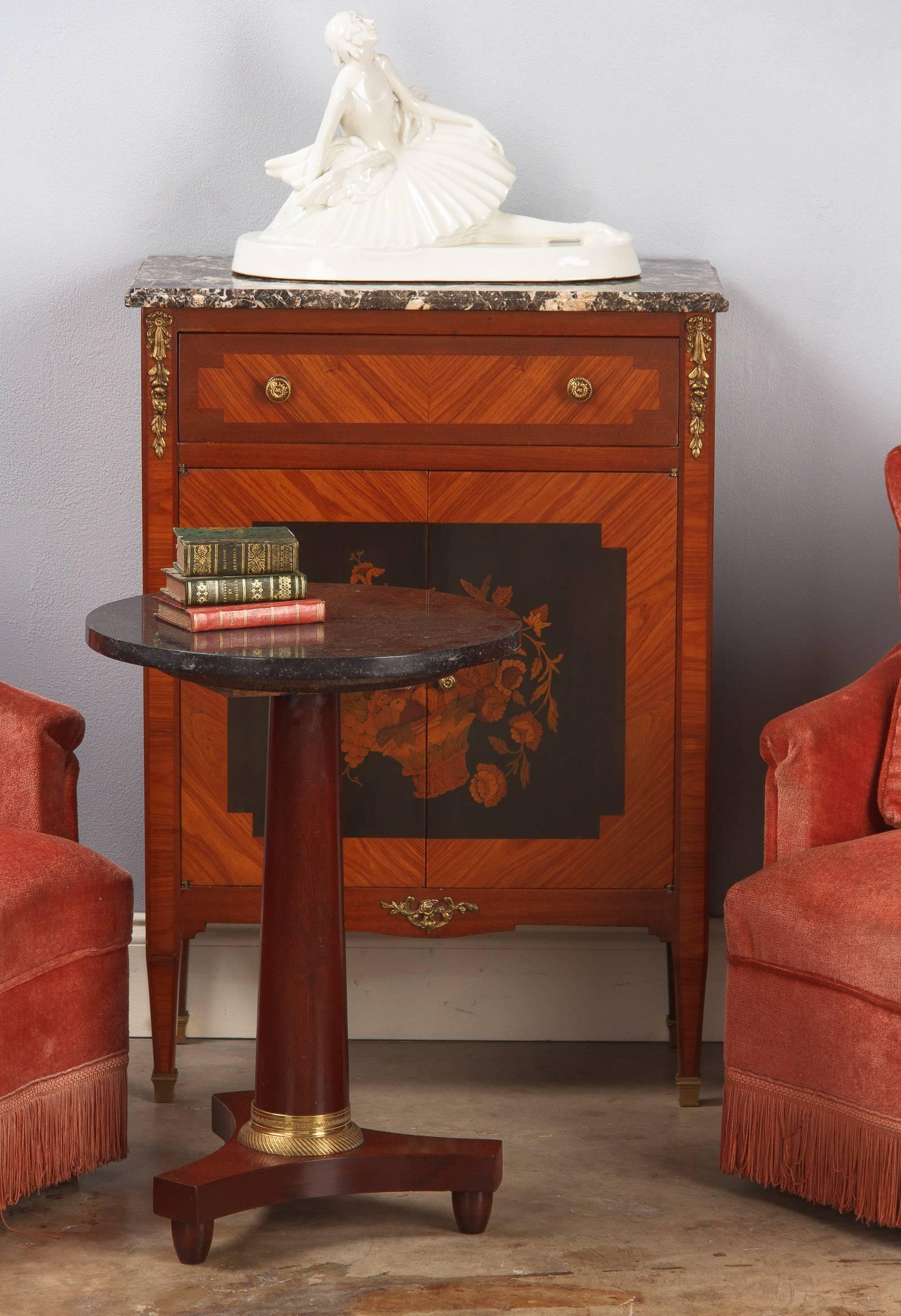 A French Empire style small pedestal table or gueridon made of red mahogany with a decorative brass ring and topped with a round black marble. Quite a lovely table with lots of character. Perfect for a side table or between two chairs. 