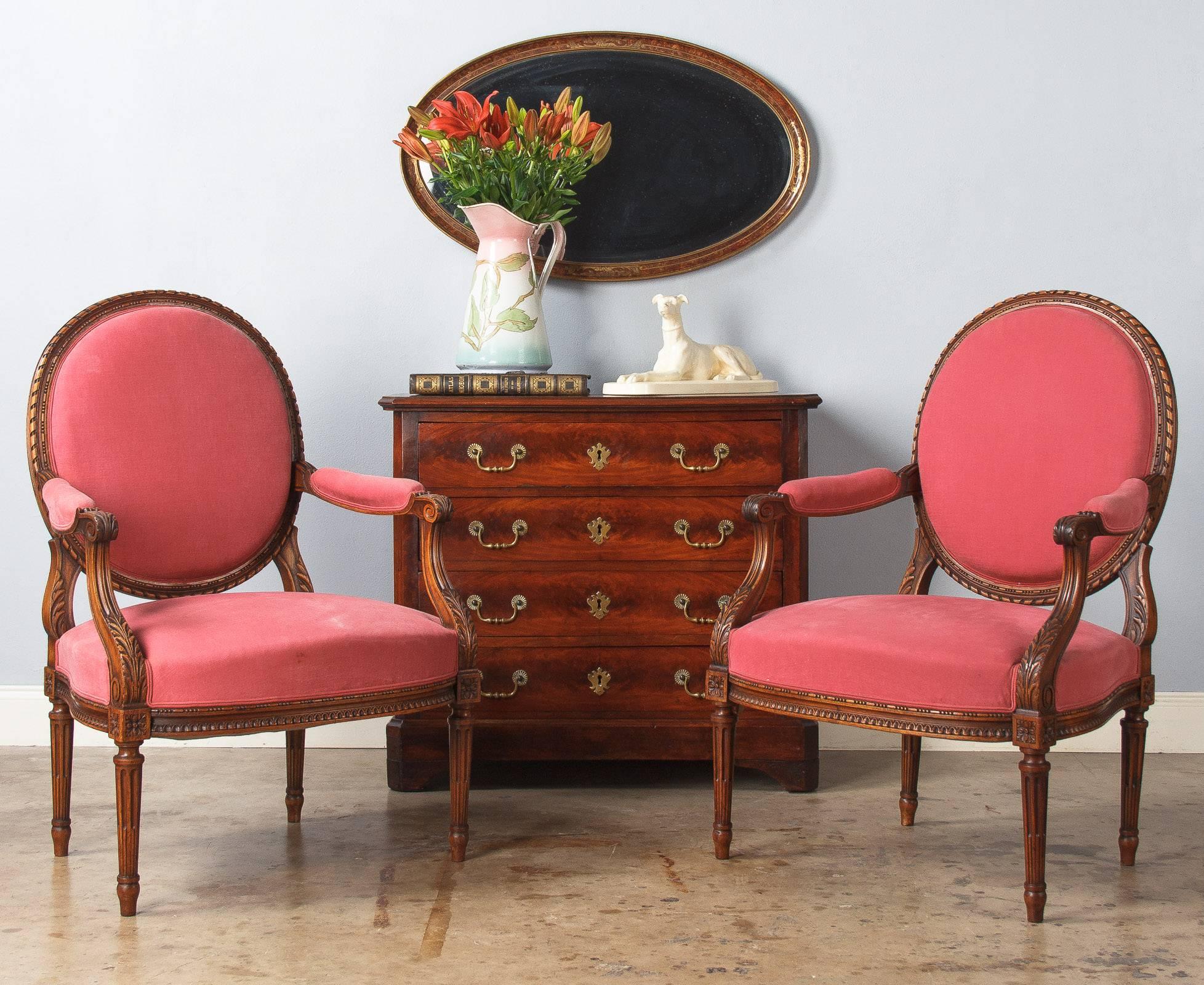 A wonderful pair of Louis XVI style cabriolet armchairs, circa 1900s, made of cherry wood with medallion backs. Abundant and delicate carvings including beading, rais-de-coeur, scrolls and acanthus leaves. Traditional Louis XVI style cable fluted