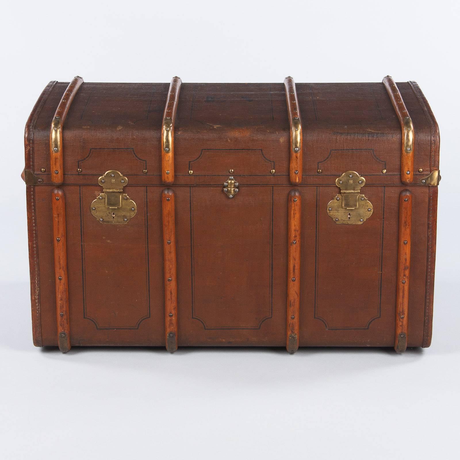 A French traveling trunk from the early 1900s purchased in Lyon. The trunk is made of poplar lined with a dark brown oil cloth with a black trim and the engraved initials E.V. The side handles are leather and the locks are brass. The inside features