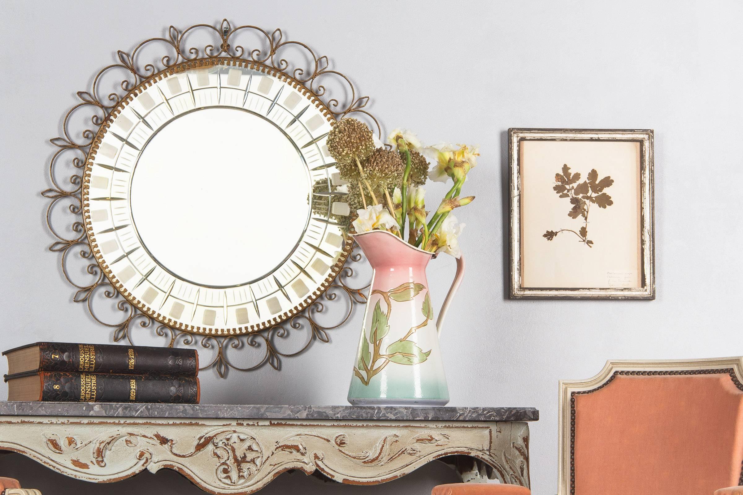 A very decorative Mid-Century round mirror with a scrolled brass frame. The etched glass has geometrical designs of frosted rectangles. The mirror glass is cloudy at parts.