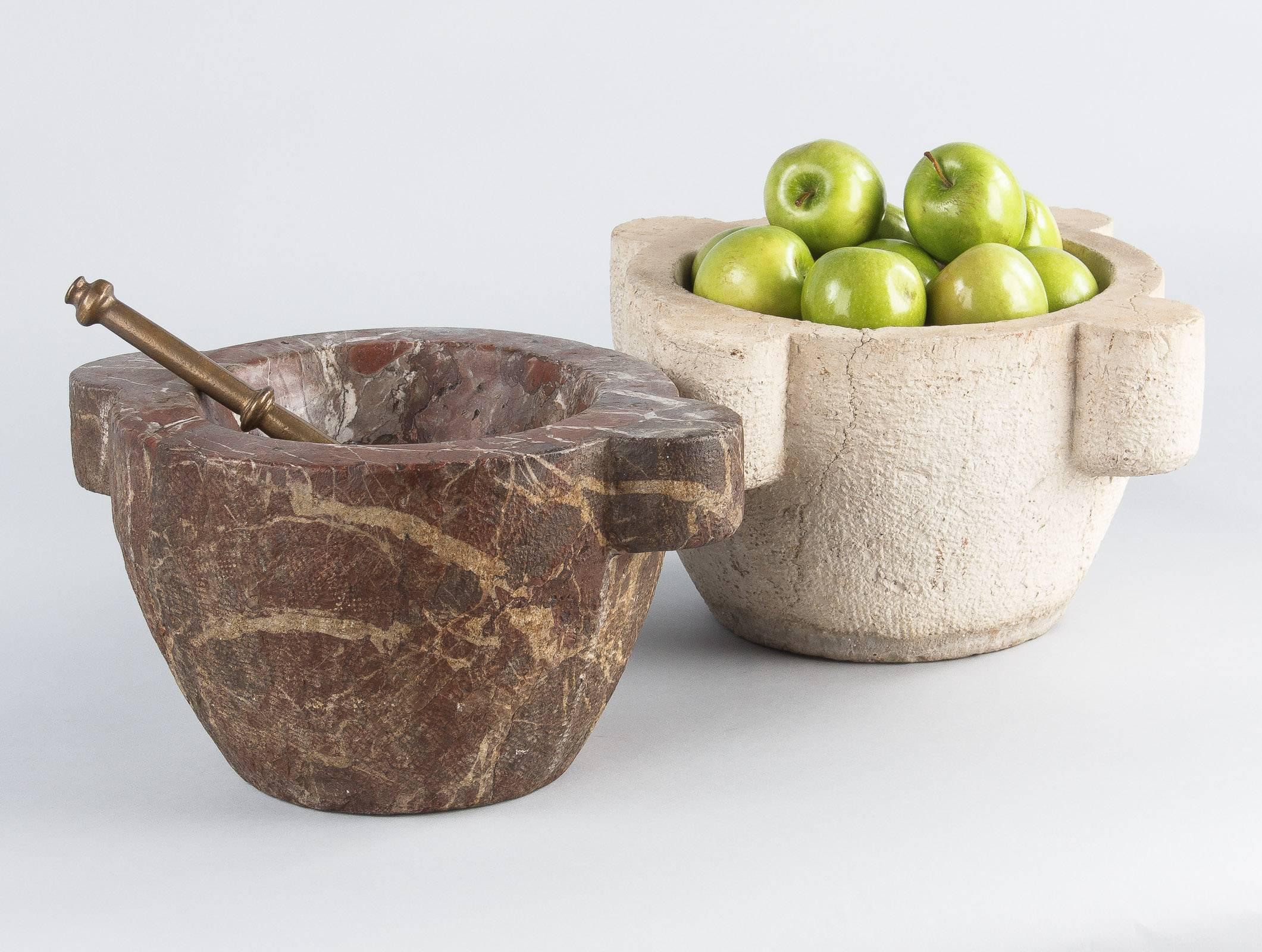 A splendid purple marble apothecary mortar with brass pestle, 1800s. The large, solid marble is a reddish purple with thick white seams and thin black veins. Either side has a semi-circular projected handle. The entire outside is rough hewn, with a