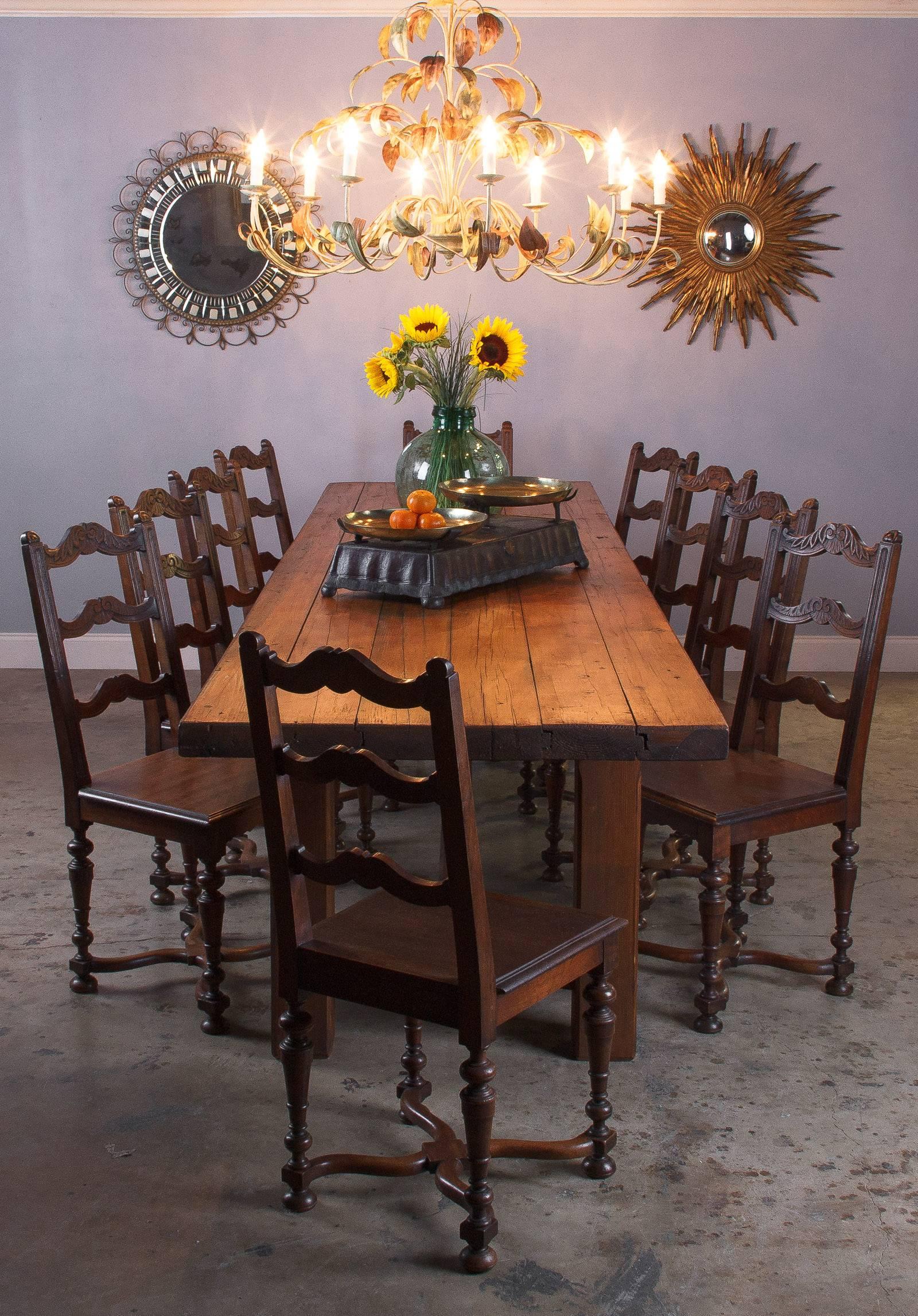 A French country style farm table that measures over 11 feet in length and can sit up to 14 people. The table is made of stained pinewood and has straight square legs and a long stretcher. The top is made of 2