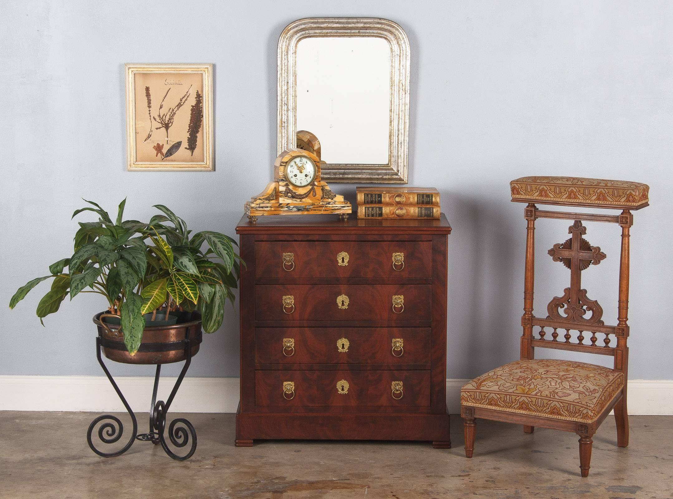 A delightful petite chest of drawers in the French Empire style, circa 1920s. Exquisite flame mahogany veneer creates fantastic visual interest, especially on the top and front of the chest. The commode rests on bracket feet and features four