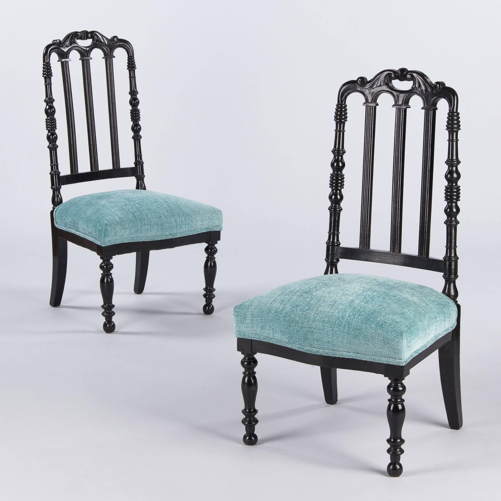 A pair of Napoleon III Chauffeuses, low chairs designed to sit by the fireplace. Made of ebonized pear wood and recently re-upholstered in pale blue, they have a contemporary feel. Dating from the 1870s, these chairs feature a slat back with a