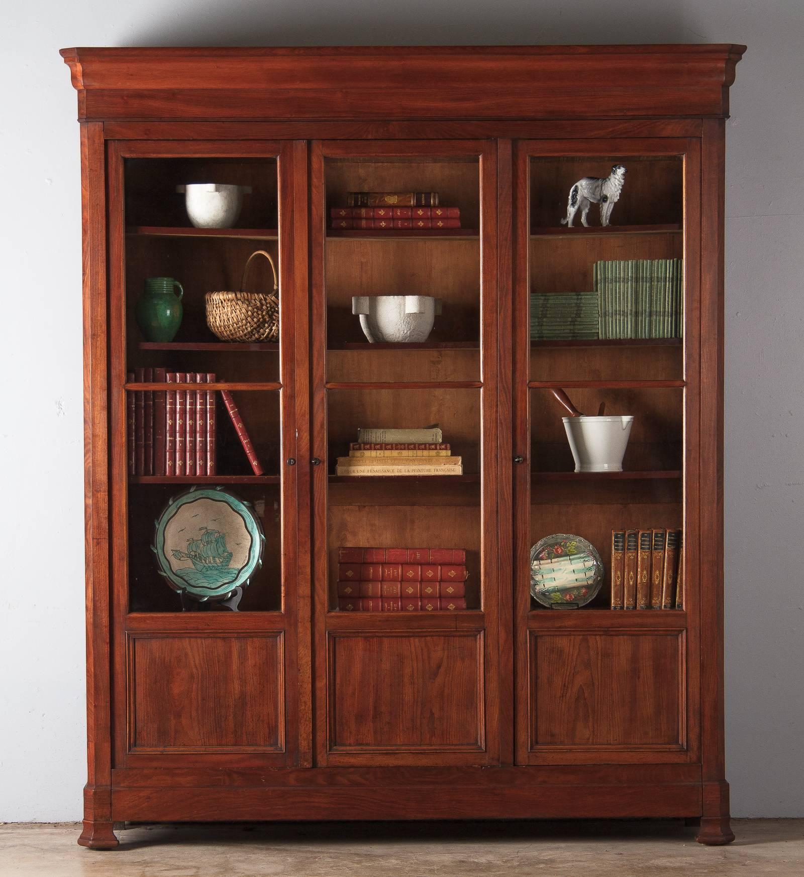 A wonderful Louis Philippe period three-door bookcase from Lyon, France, circa 1830s. The bookcase is made of solid walnut and walnut veneer. The paneled doors have their original glass. The inside is 14