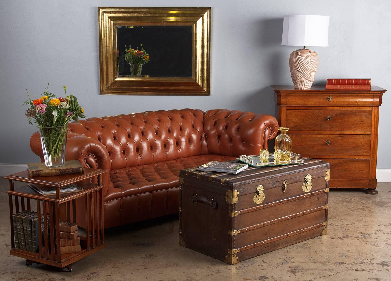 A vintage Chesterfield three-seat sofa in caramel colored tufted leather, circa 1960s. Tight button tufts dot the seat, backrest, arms and front, the sides and back are flat. Antique nailhead trim highlights the front corners and graceful curve of