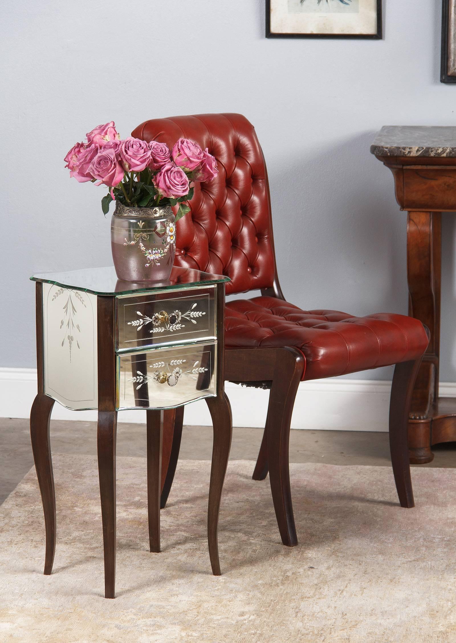 A fetching and petite midcentury Venetian glass mirrored chest of drawers with mahogany legs, circa 1950s. Perfect for a bedside table or cabinet. The mirrored top has a sinuously scalloped profile with bevelled edges and a languid etched trim line.