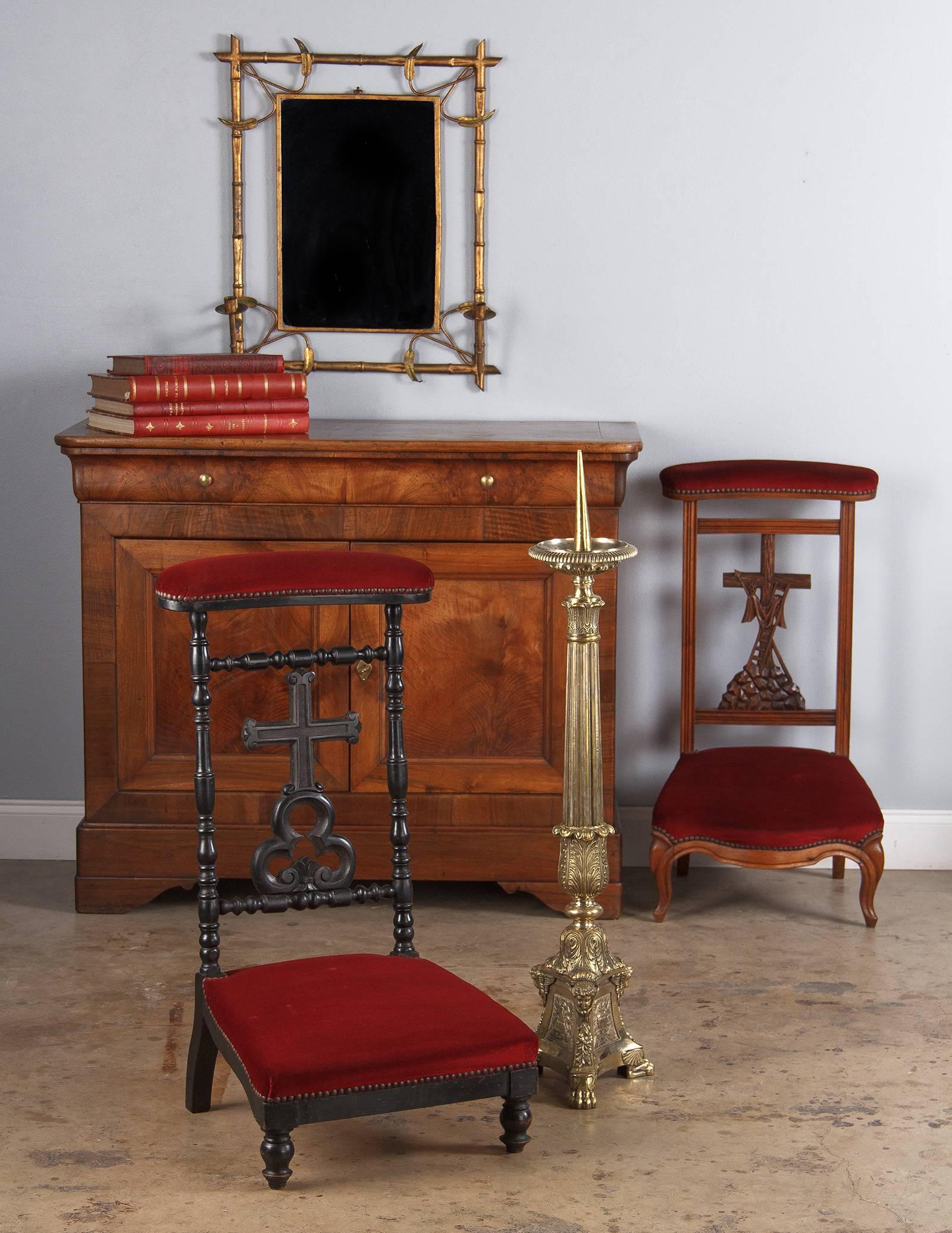 A prie dieu chair, prayer kneeler, in ebonized pearwood with red velvet upholstery from the period of Napoleon III, circa 1870. The frame features elaborate baluster turning with a detailed centerpiece of a relief carved cross above a flourished