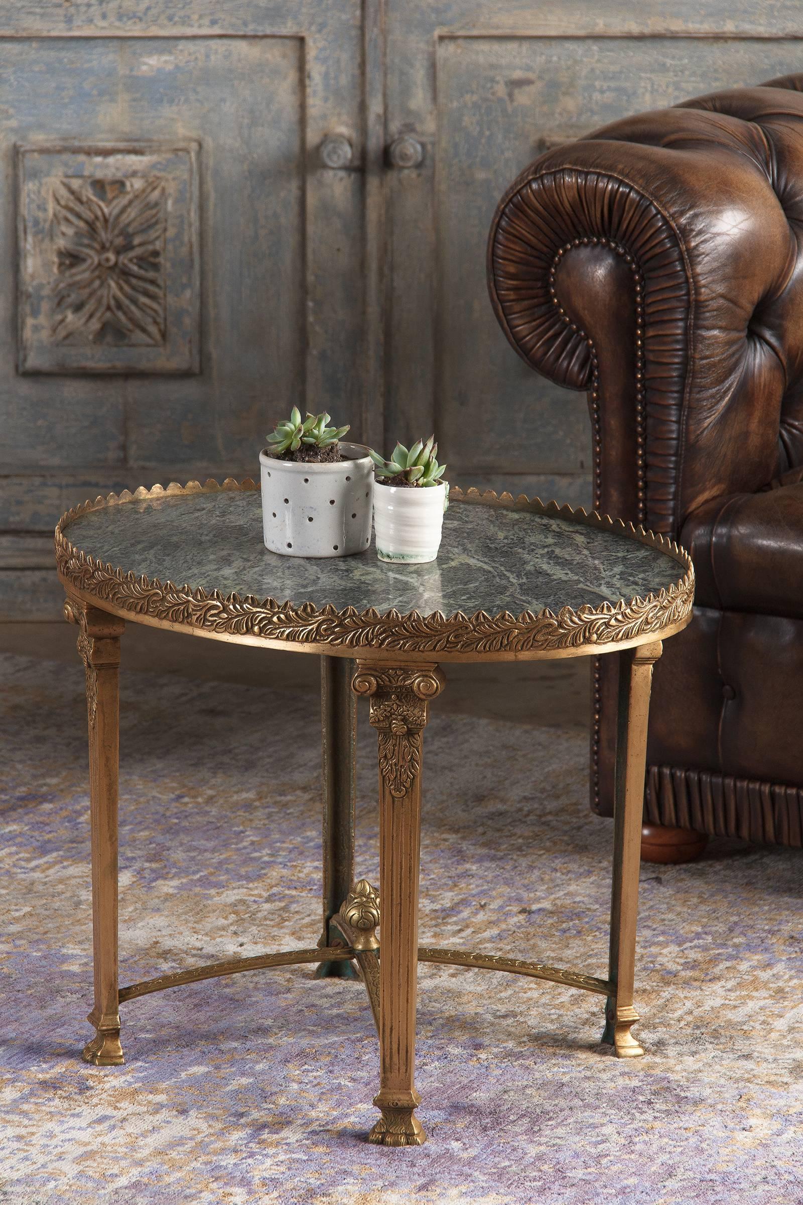 Vintage gilt bronze marble-top side table in the Empire style, circa 1950. An ornate gilded bronze base with a peaked, heavily foliate gallery and fluted Corinthian column legs culminating in clawed feet. The cruciform stretcher is graced with water