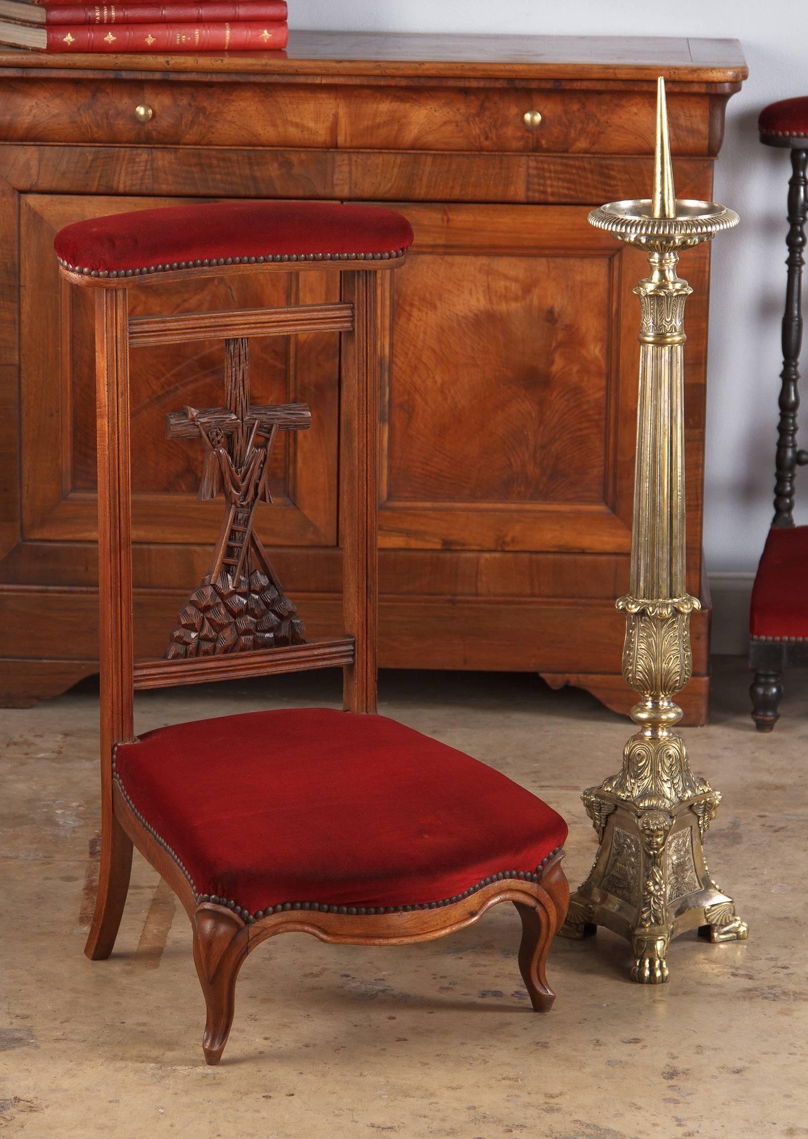 A pious Louis Philippe prie dieu, prayer chair, in walnut and red velvet, circa mid-1800s. The chair's focal point is a carved back piece displaying the cross after Christ's removal, the spear and ladder are propped up against it. Molded frame
