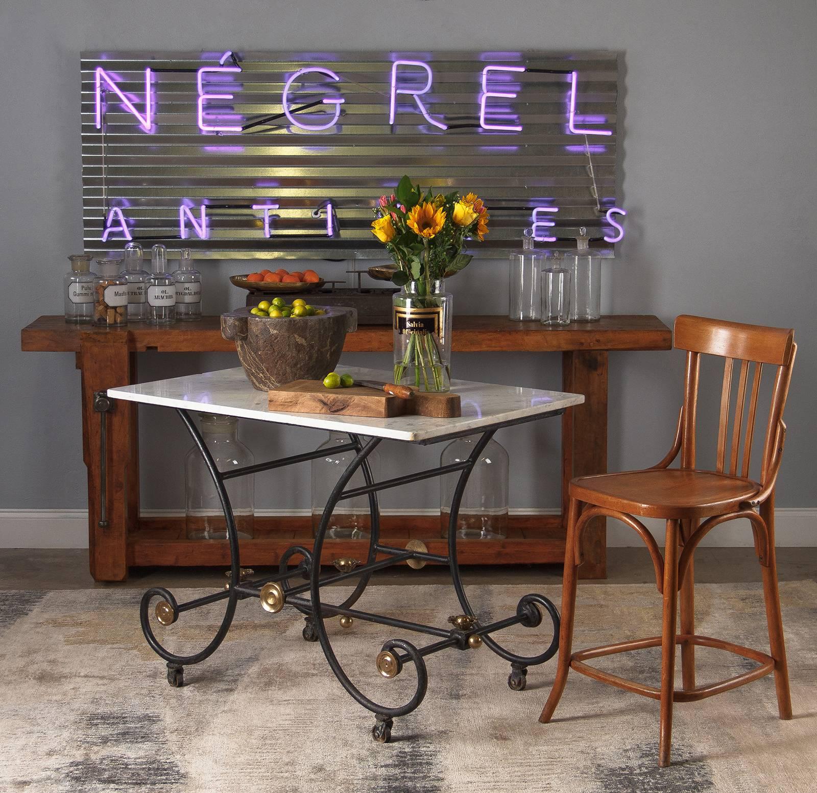 A charming marble-top iron framed butcher's table, circa 1900. The delicate scrolling structure of the iron base combined with the lightly veined white Carrara marble top give the piece a very airy feel. Black wrought iron legs bow in from the top,