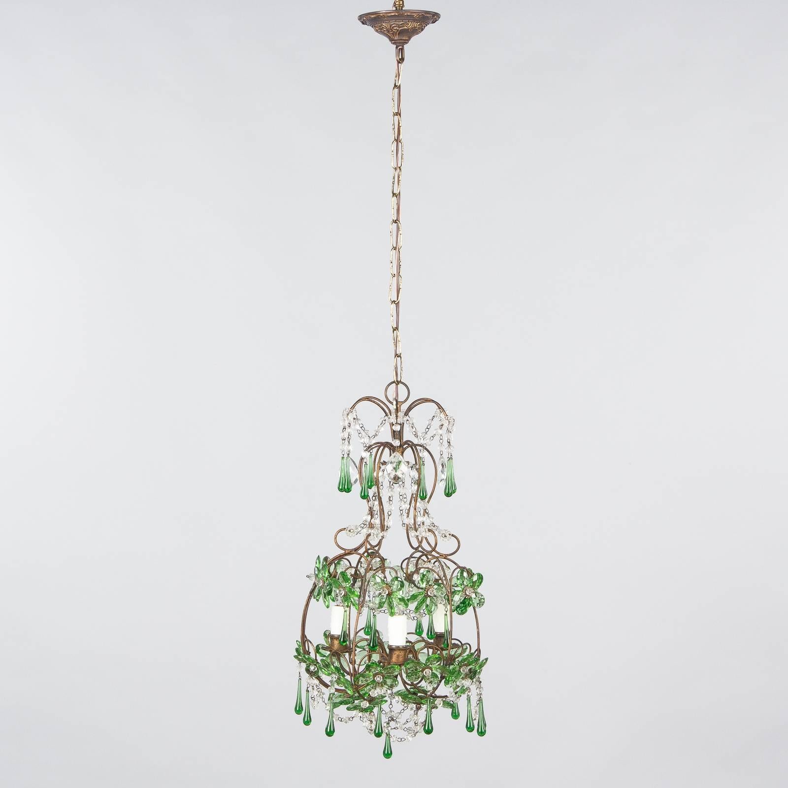 A vibrant green glass and crystal chandelier, French, circa 1920. This piece brings a hit of color as well as illumination. The scrolled gilded metal frame creates a dainty cage that cradles three lights and supports multiple tiers of glass and
