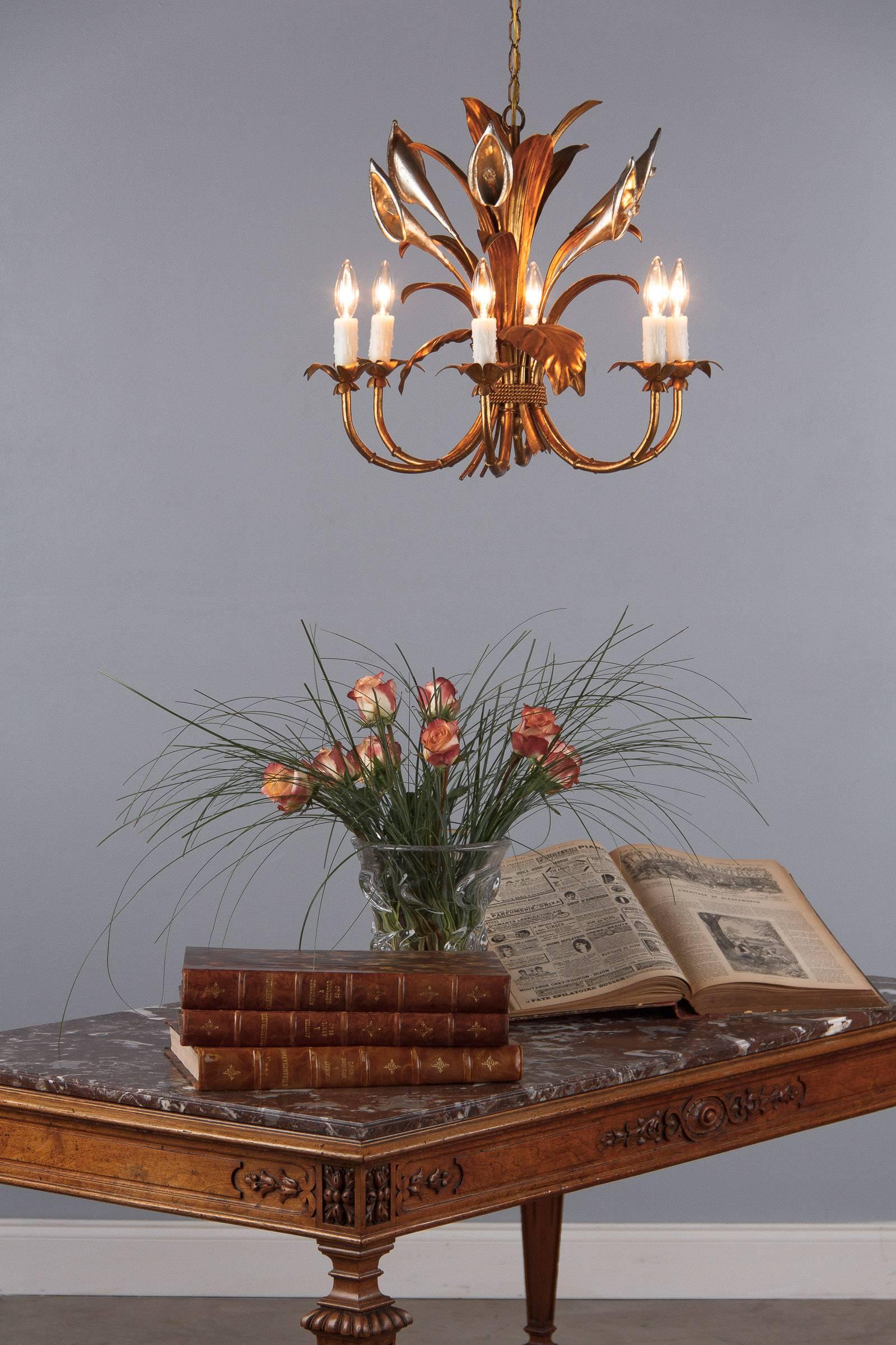 A very decorative gilded metal chandelier with an antique finish. The fixture has six arms newly rewired for candelabra bulbs. The chandelier is designed with leaves tightened with a rope and silver metal lilies with crystal prisms as pistils. The