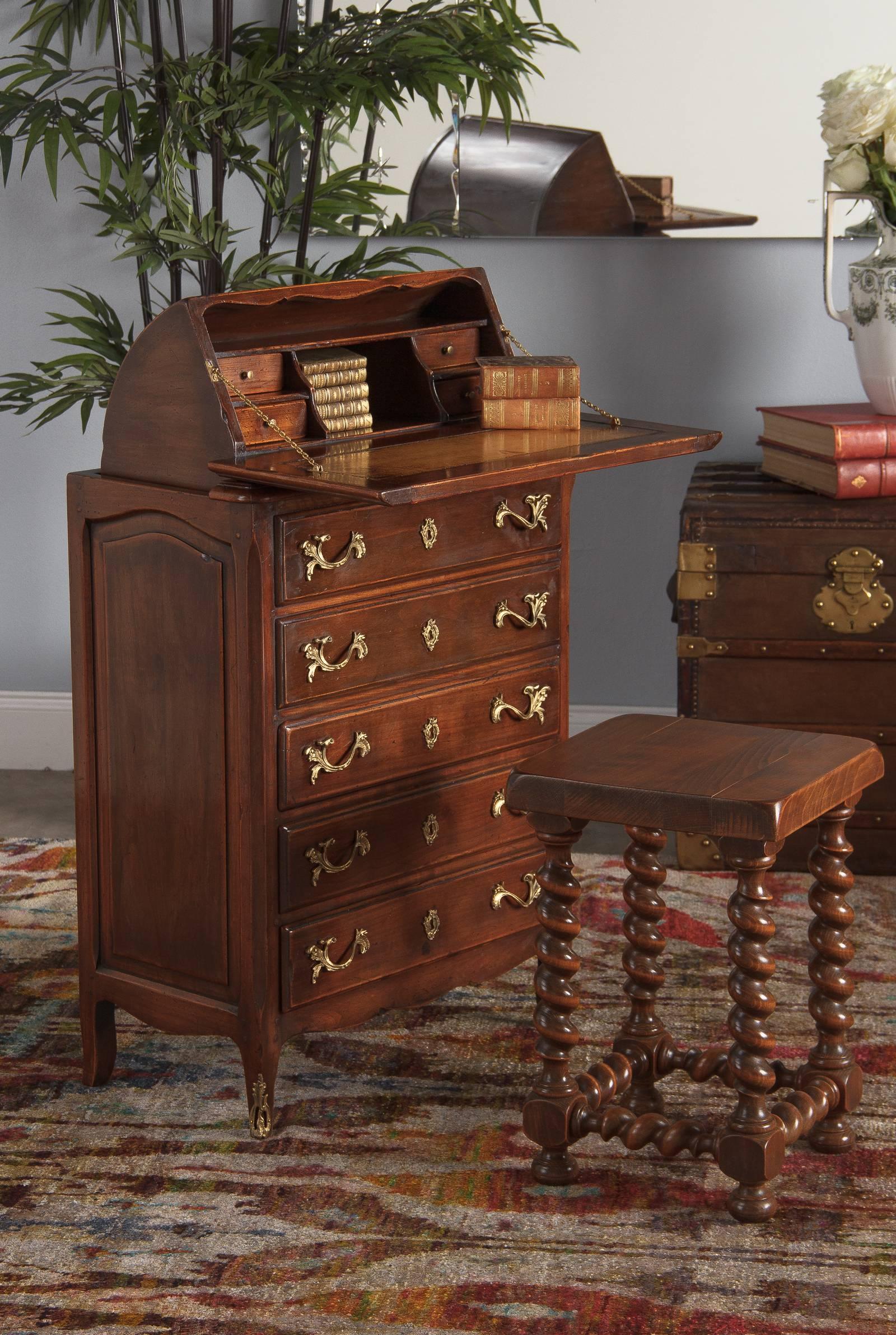 A Louis XV style chest in walnut with a roll out collapsible secretaire, circa 1920. The top two drawers are false, covering the space where the secretaire is nestled when closed. Pulling the back edge up and over rolls out the little cabinet with