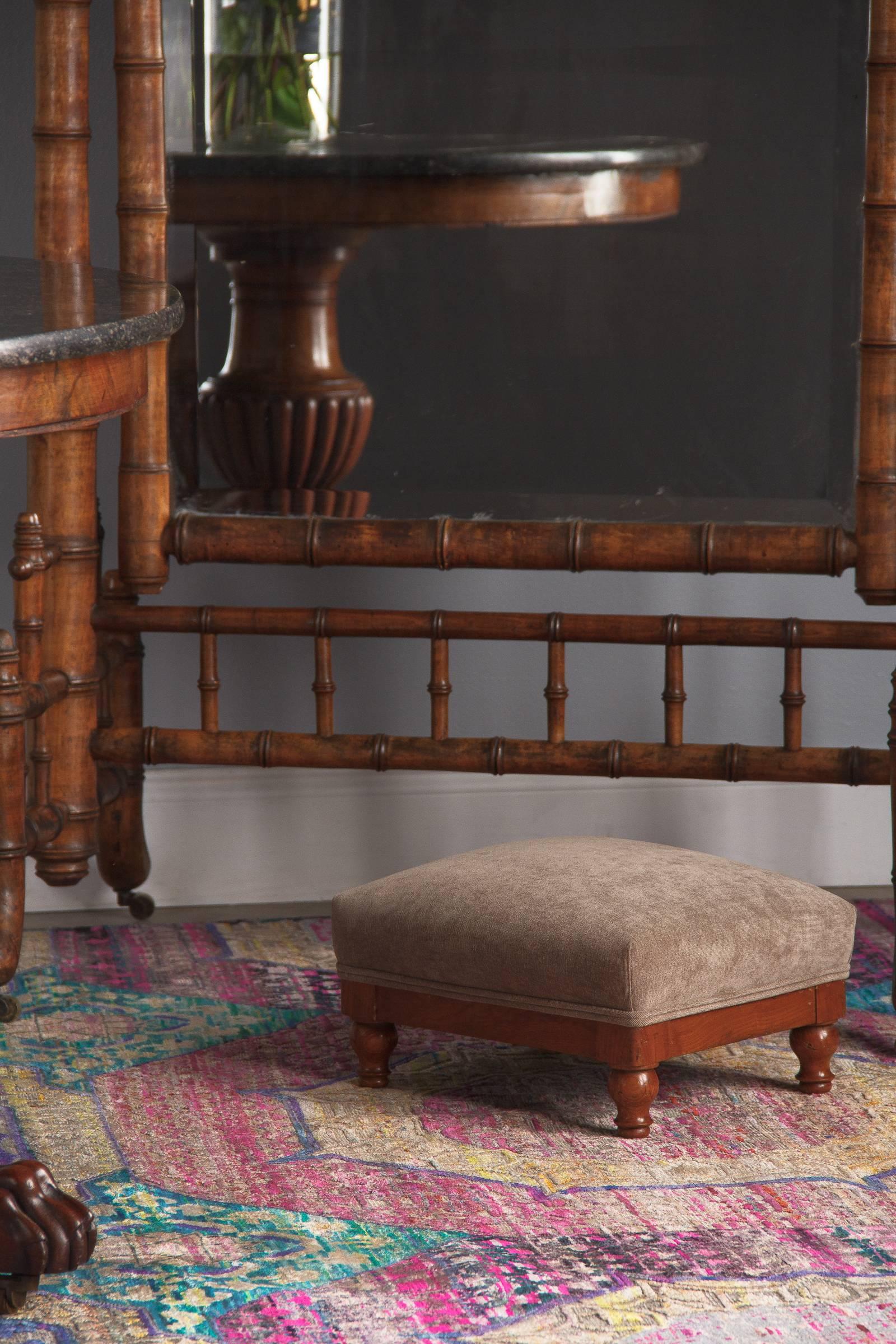A petite upholstered oak footstool in the Louis Philippe style, French, circa 1900. The oak frame has simple square corners and attractive little baluster feet, all finished with a warm varnish. New warm-toned taupe grey upholstery has tucked