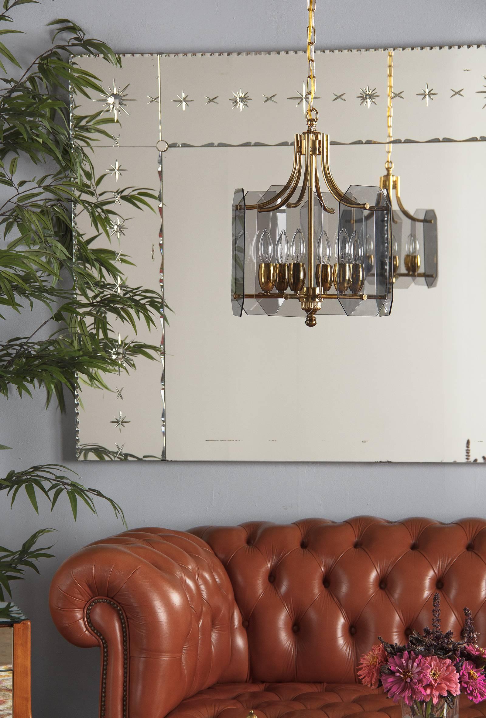 Midcentury vintage brass and smoked glass panel chandelier, French, circa 1960. Six rectangular glass panels with notched edges encircle the chandelier, attached to the structure by two levels of tubular brass shafts. A central shaft connects to six