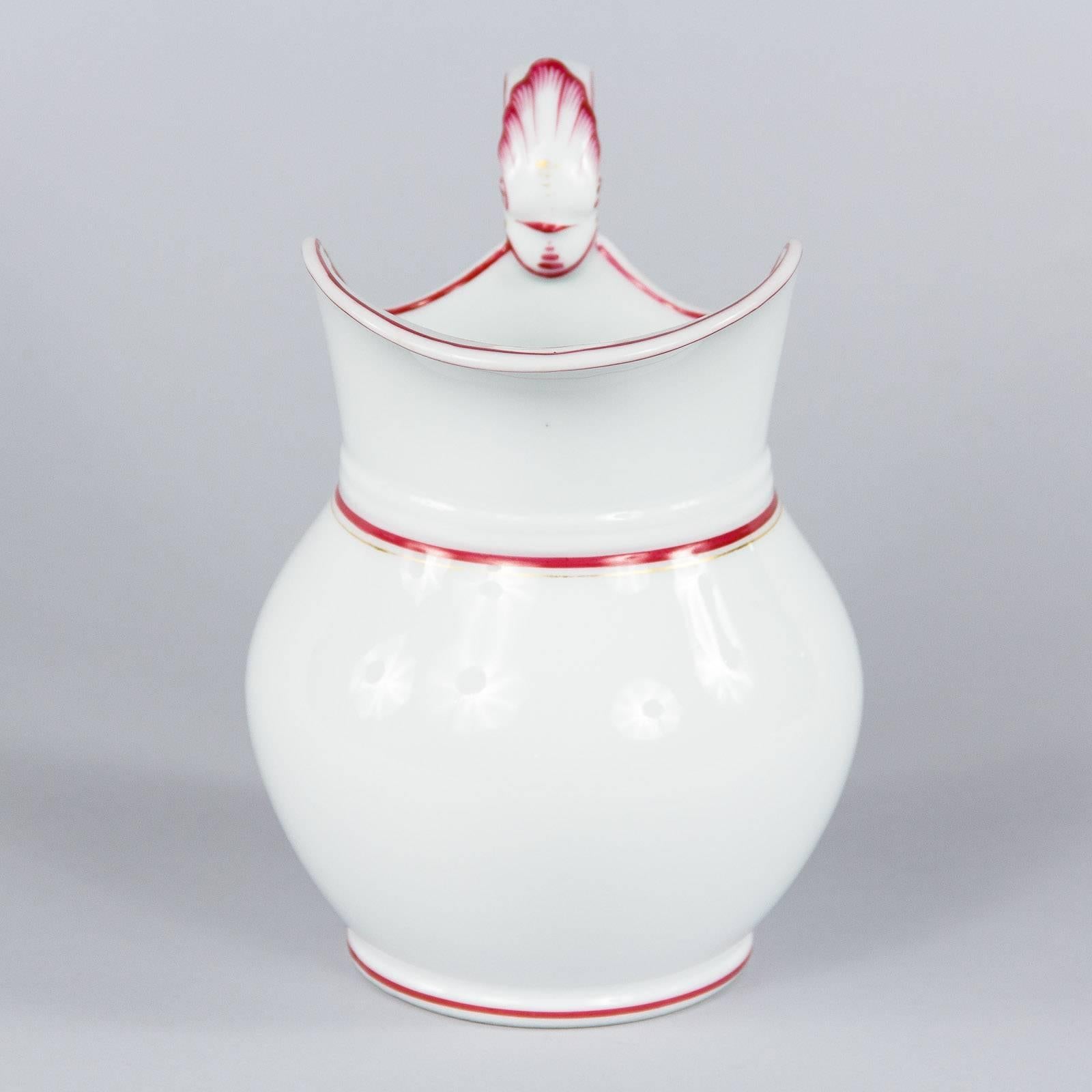 A French pitcher in white ceramic with painted red trim and gilt details, circa 1950. Charming proportions, with a round belly and wide mouth. Cranberry red trim lines are painted throughout, including around the base, inside and outside the profile