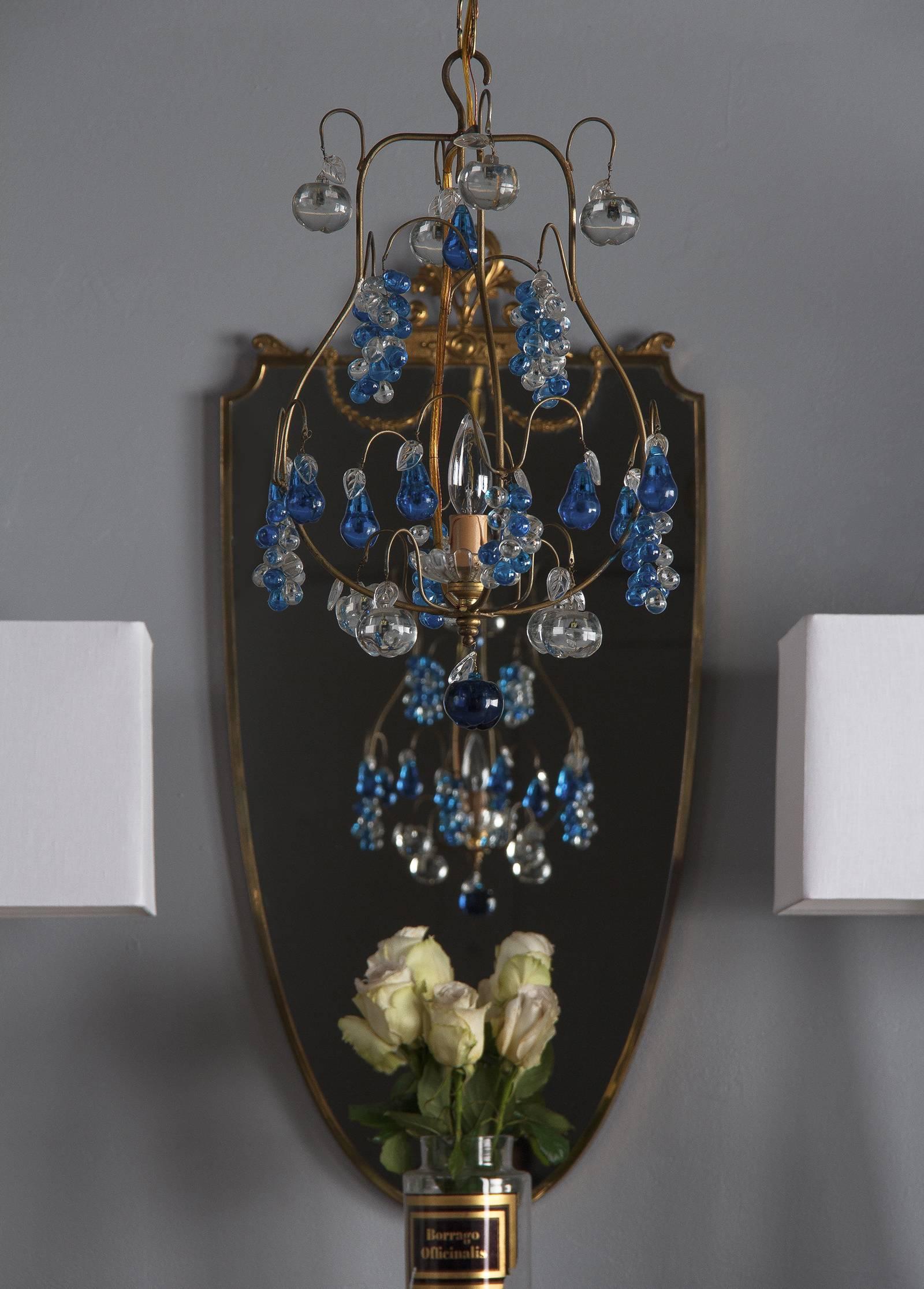 A charming Mid-Century Murano chandelier made of brass with cobalt blue and clear glass pendants in the shape of fruits (grapes, apples and pears). The fixture takes one single small socket light bulb up to 60 w. Measure: The adjustable chain and