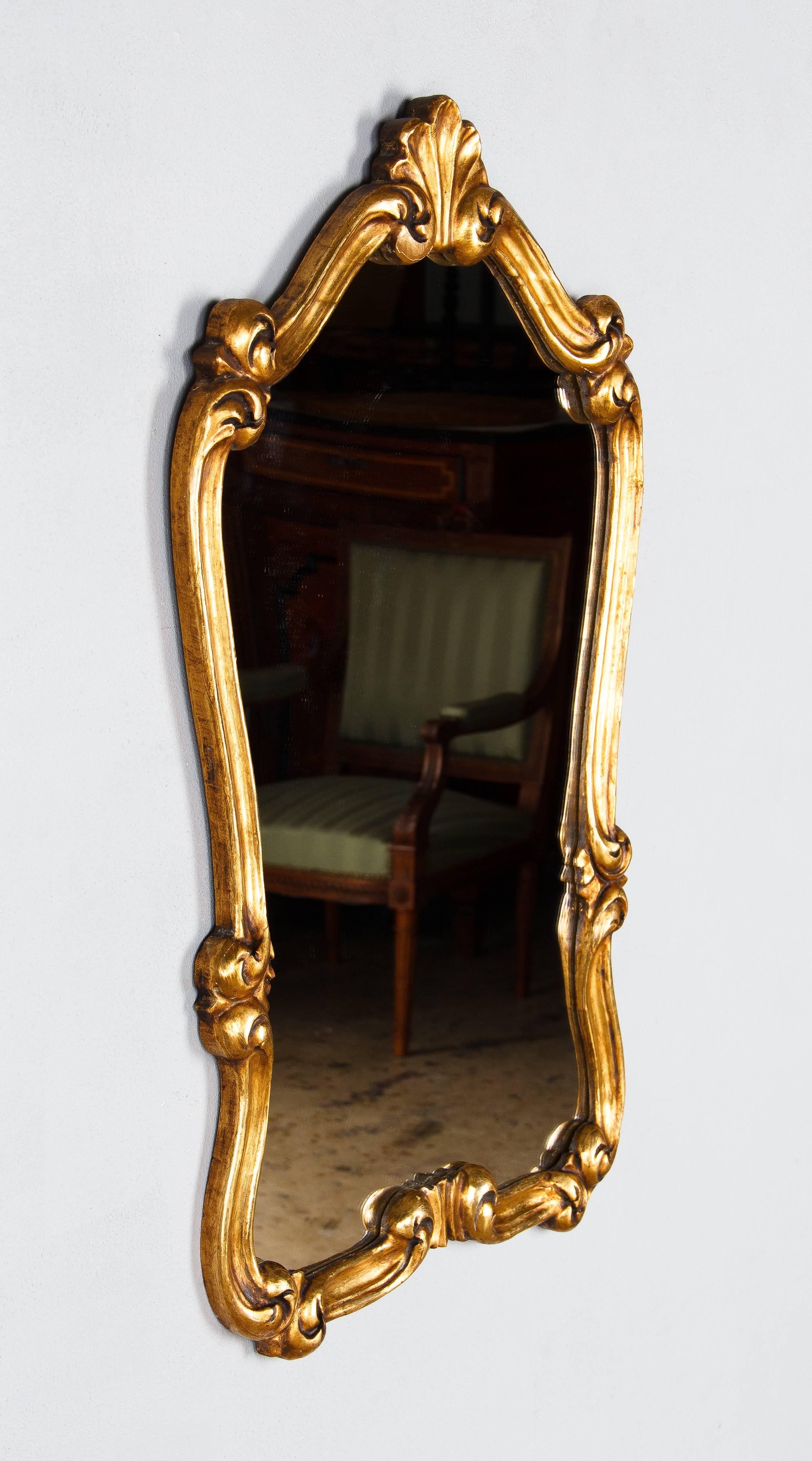 A very elegant gold leaf mirror in the Louis XV style with scrolls and shell motifs. Beautiful patina! The mirrored glass is new.