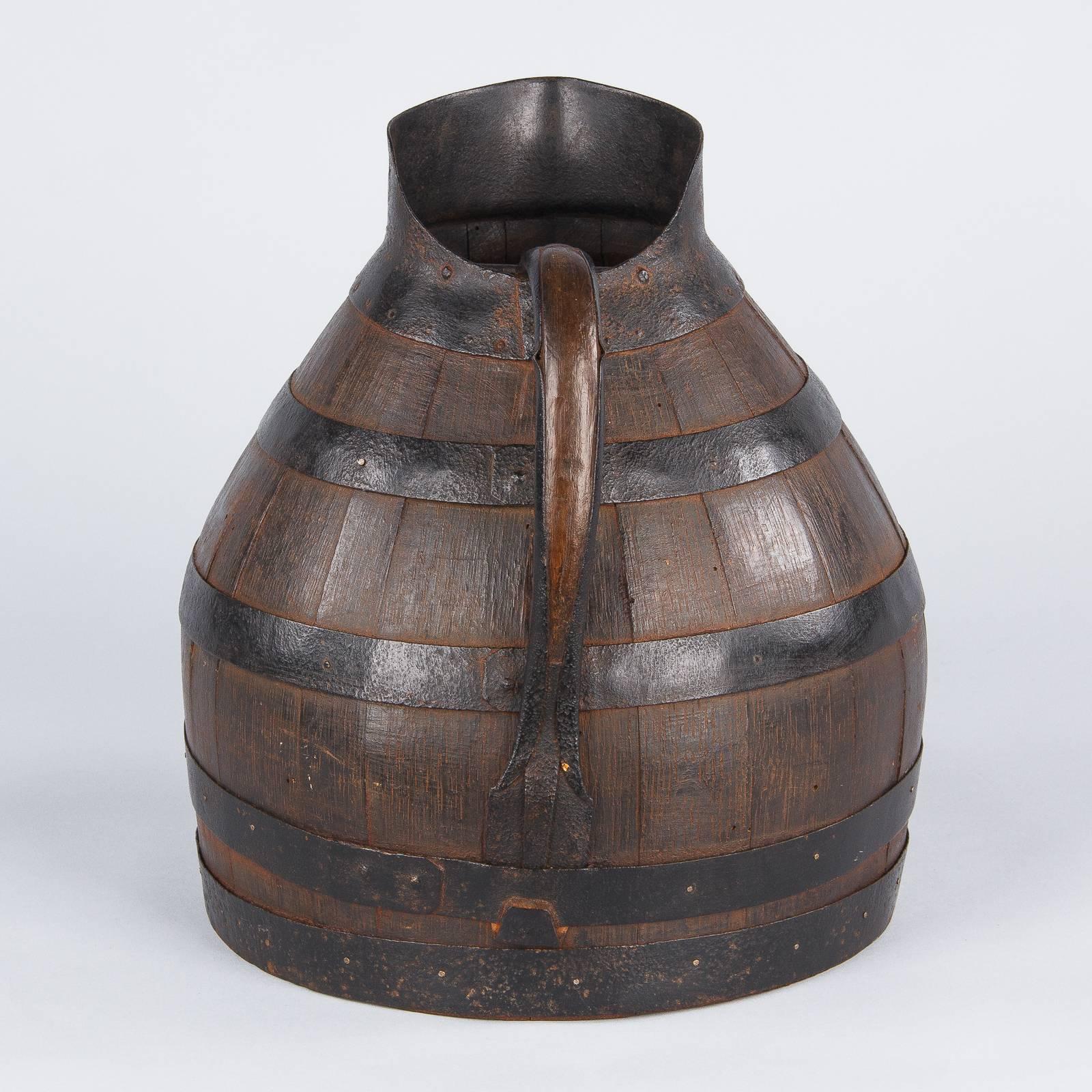 A wine pitcher made of oak with metal straps and spout purchased in Provence.