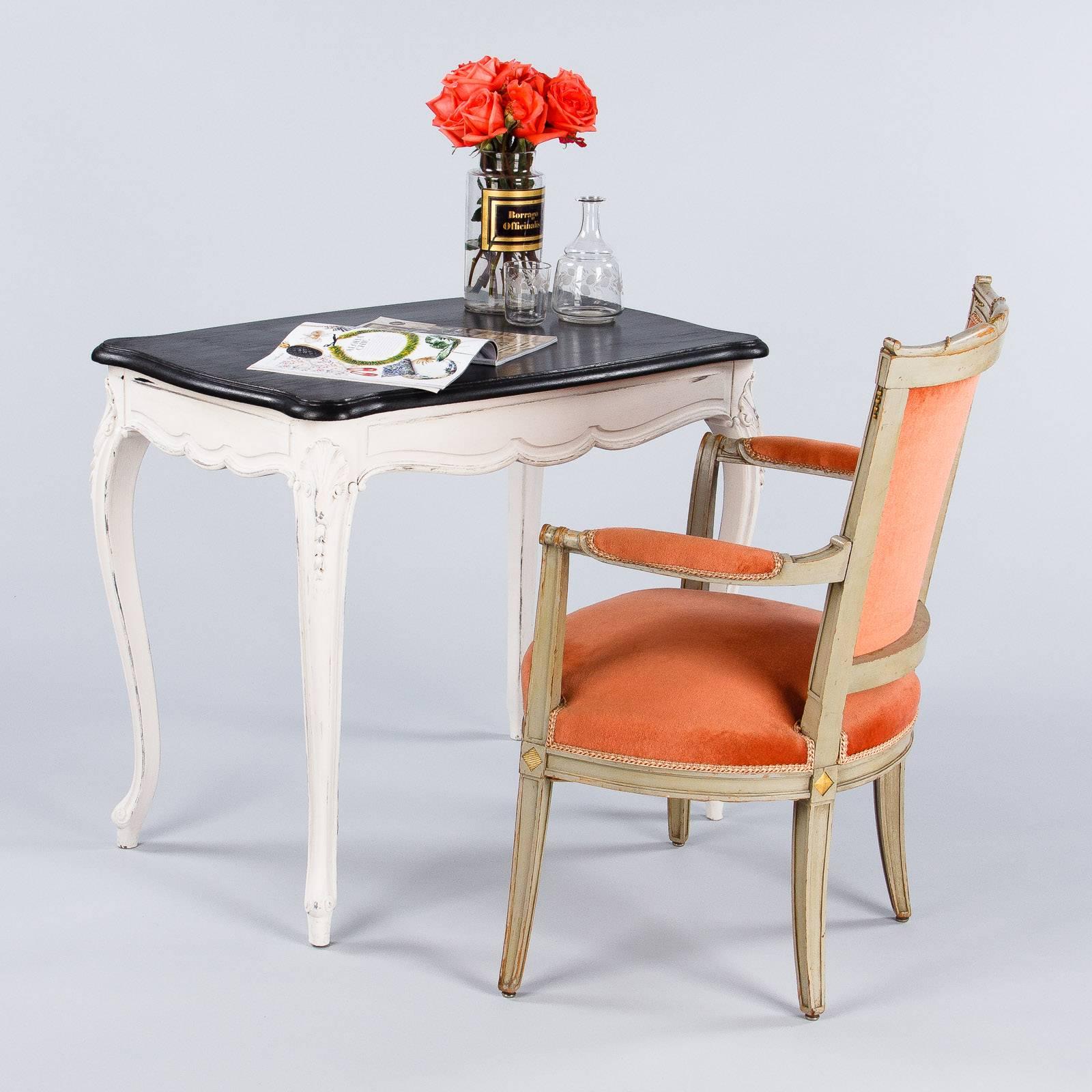 A lovely side table in the Louis XV style, circa 1900s, from the Provence region. The table has been painted with a black top and a distressed off-white base. The table features a scalloped apron, shell motif on curved legs and escargot feet.