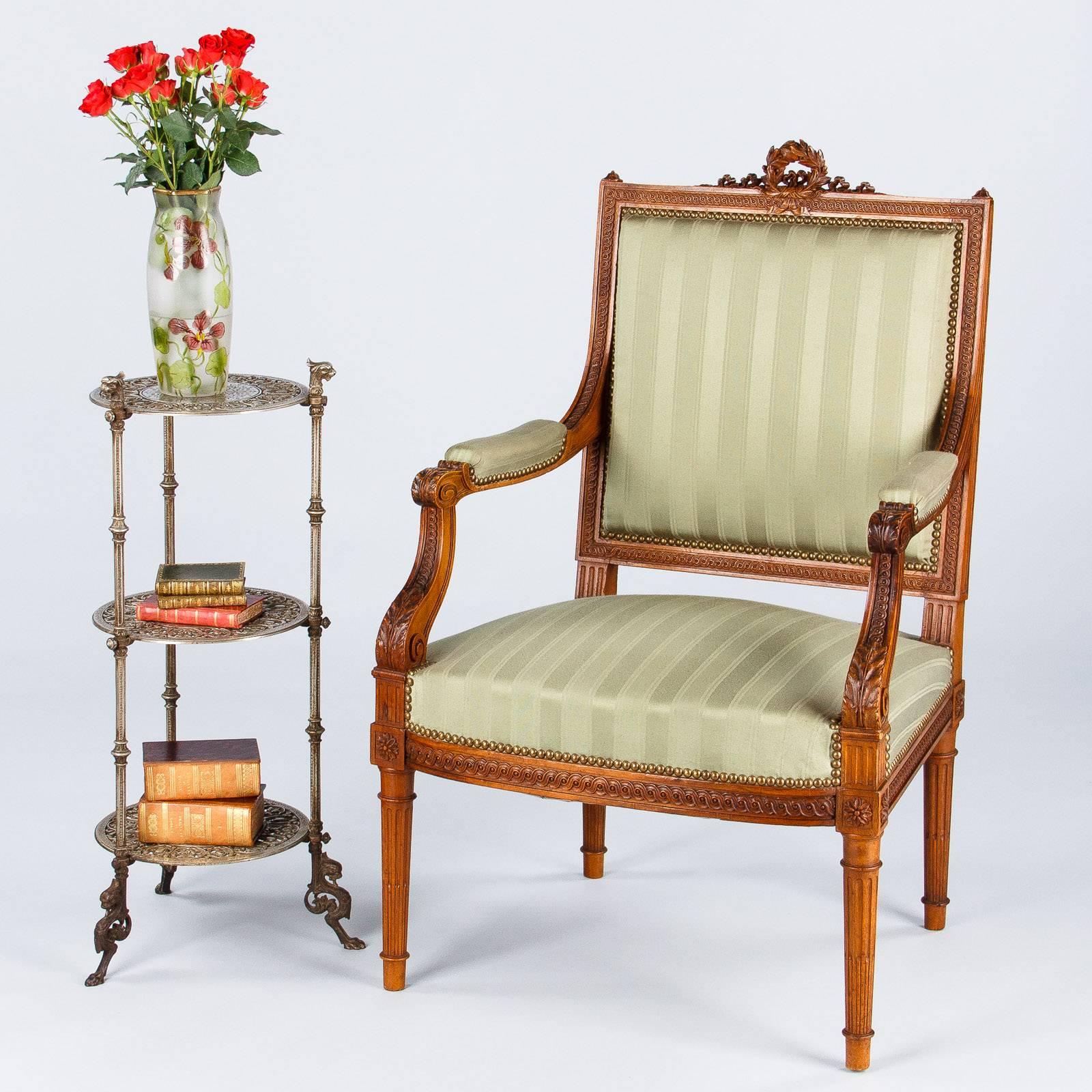 A superb Louis XVI style armchair purchased in Lyon. The armchair is upholstered in green fabric and the frame is walnut wood with beautiful carvings. The top rail features a wreath and water leaves. Acanthus leaves and gadrooning around the