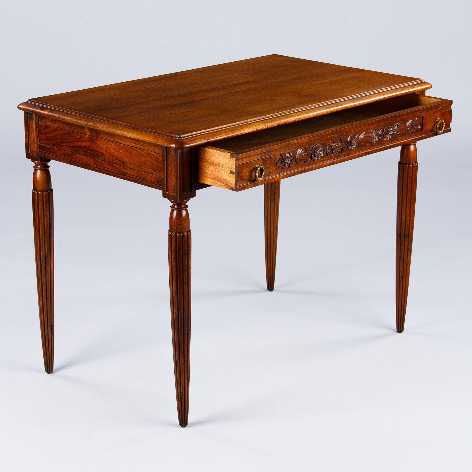 A very elegant desk in the Louis XVI style found in the Loire Region, circa 1900s. The desk is made of walnut and rests on fluted tapered legs. There are carvings of flowers and foliage on the back side and on the single drawer. The drawer features