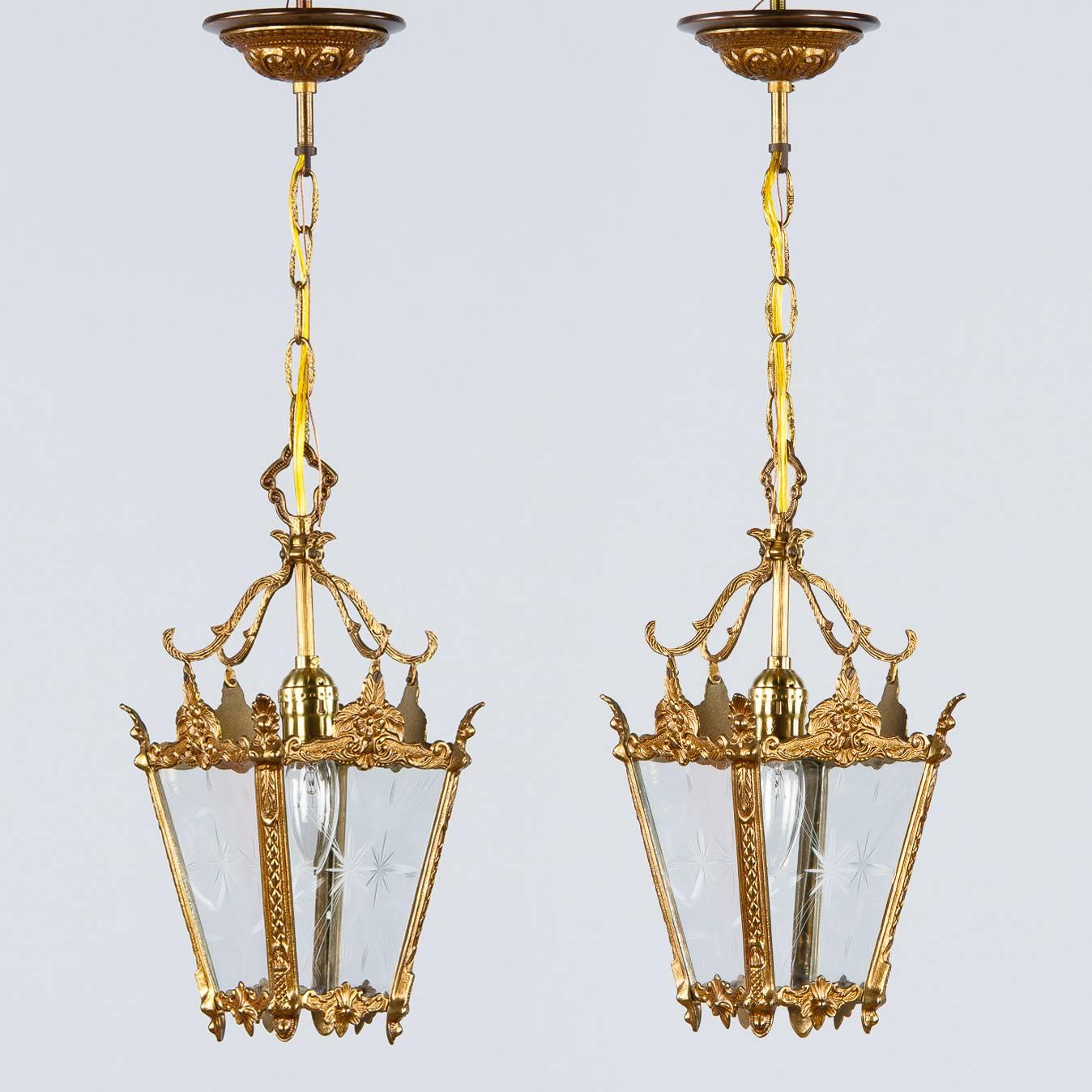 A pair of small Mid-Century French Lanterns made of ciseled brass with delicate designs of flowers and waterleaves. The etched glass panels have star motifs. Each lantern is housing a medium size light bulb, up to 100 watts each. The chain and
