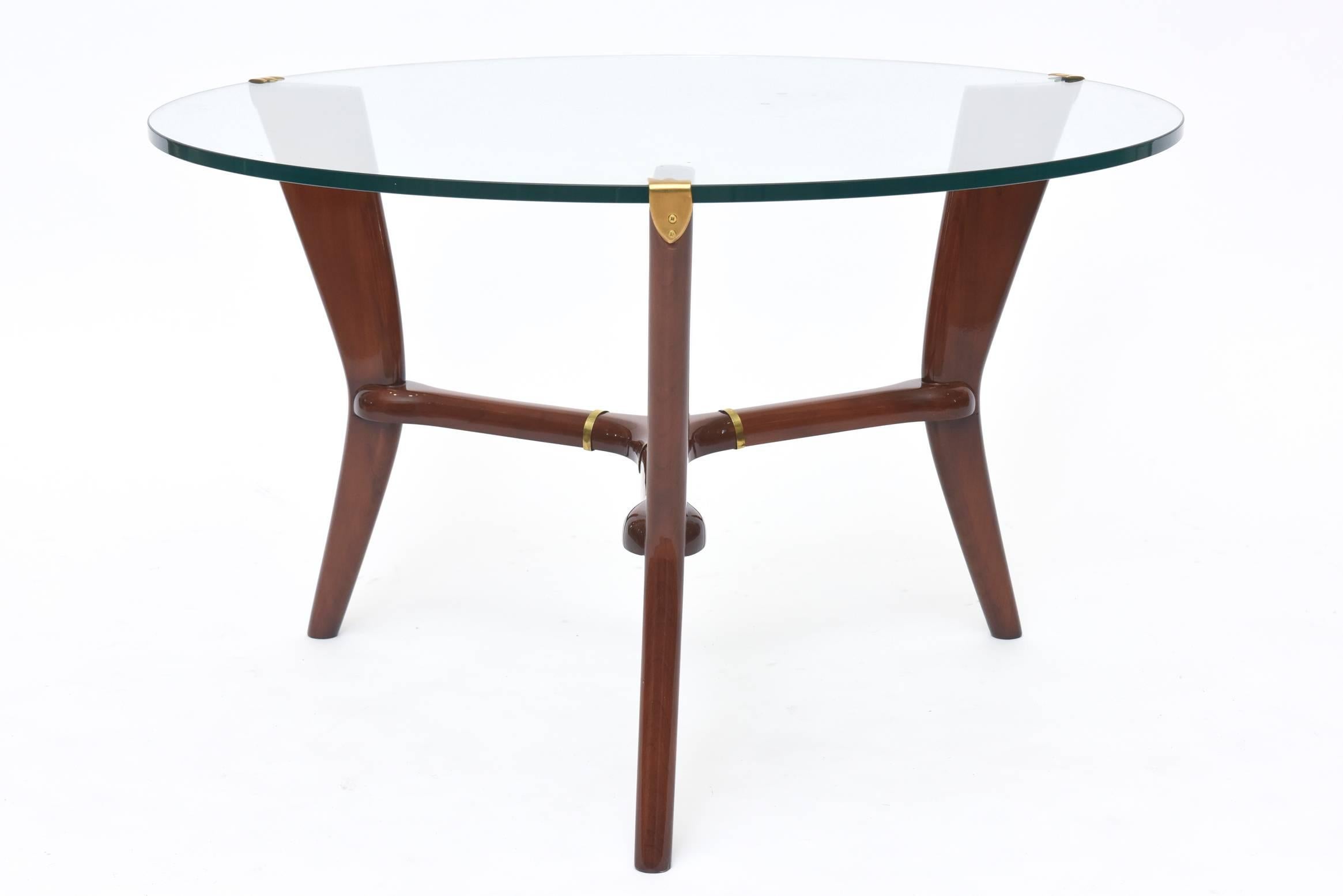 Midcentury Italian modern glass table designed by Osvaldo Borsani in a three-legged sculpted walnut pedestal base with small hints of brass hinges and a free-form round glass top.
 