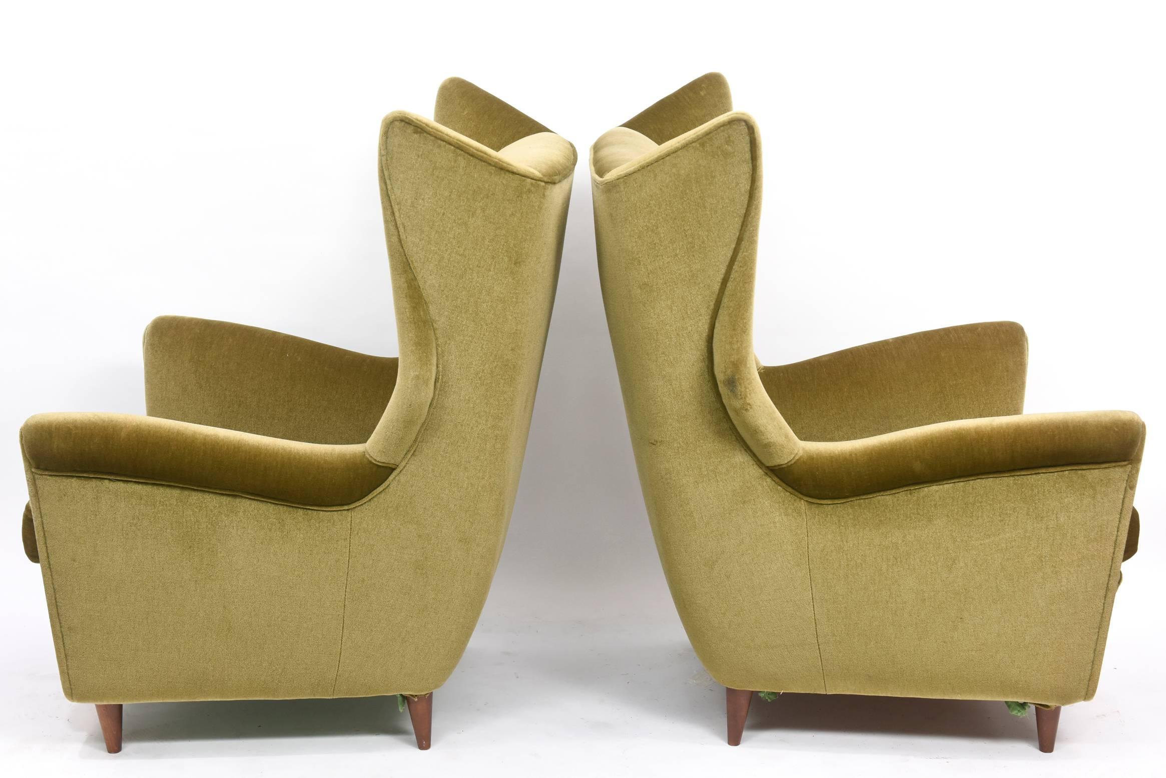 Large and imposing pair of Italian modern lounge chairs with high backs and wings on round tapering legs.