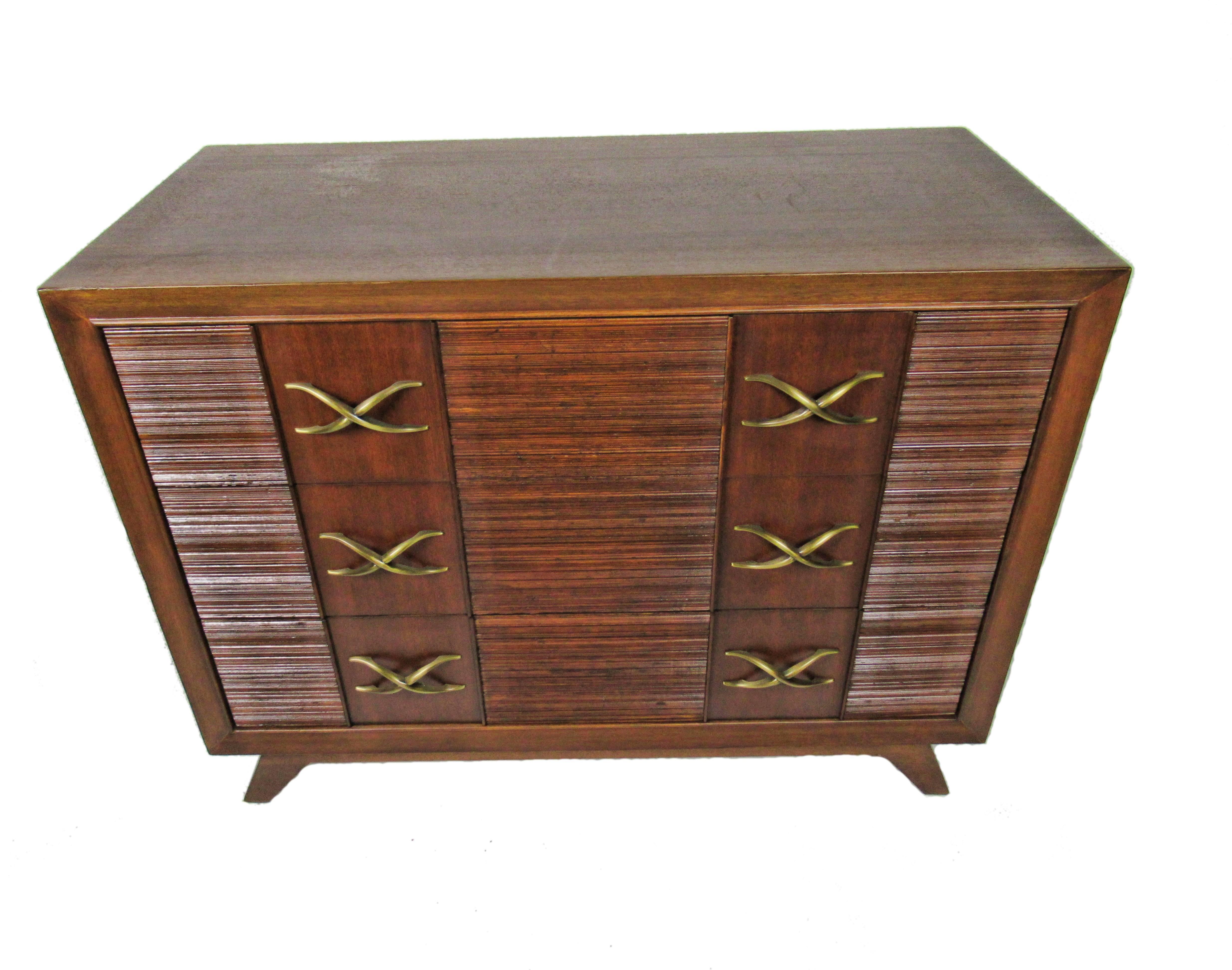 The rectangular top above three drawers with reeded and ribbed fronts with flat panels, the brass pulls in stylized 