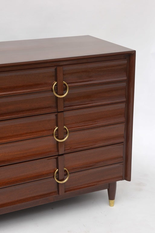 The rectangular top above a central drawer set flanked by two-drawer-three-drawer stacks with reeding and brass ring pulls, on round tapering legs with brass sabots.