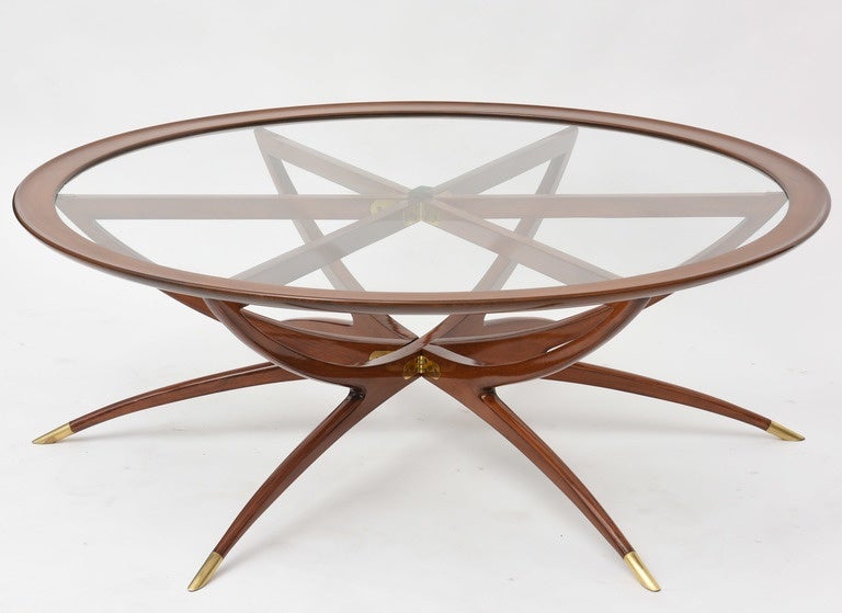 The round inset glass within a mahogany framework above six spider form legs terminating in brass caps.
Carlo de Carli