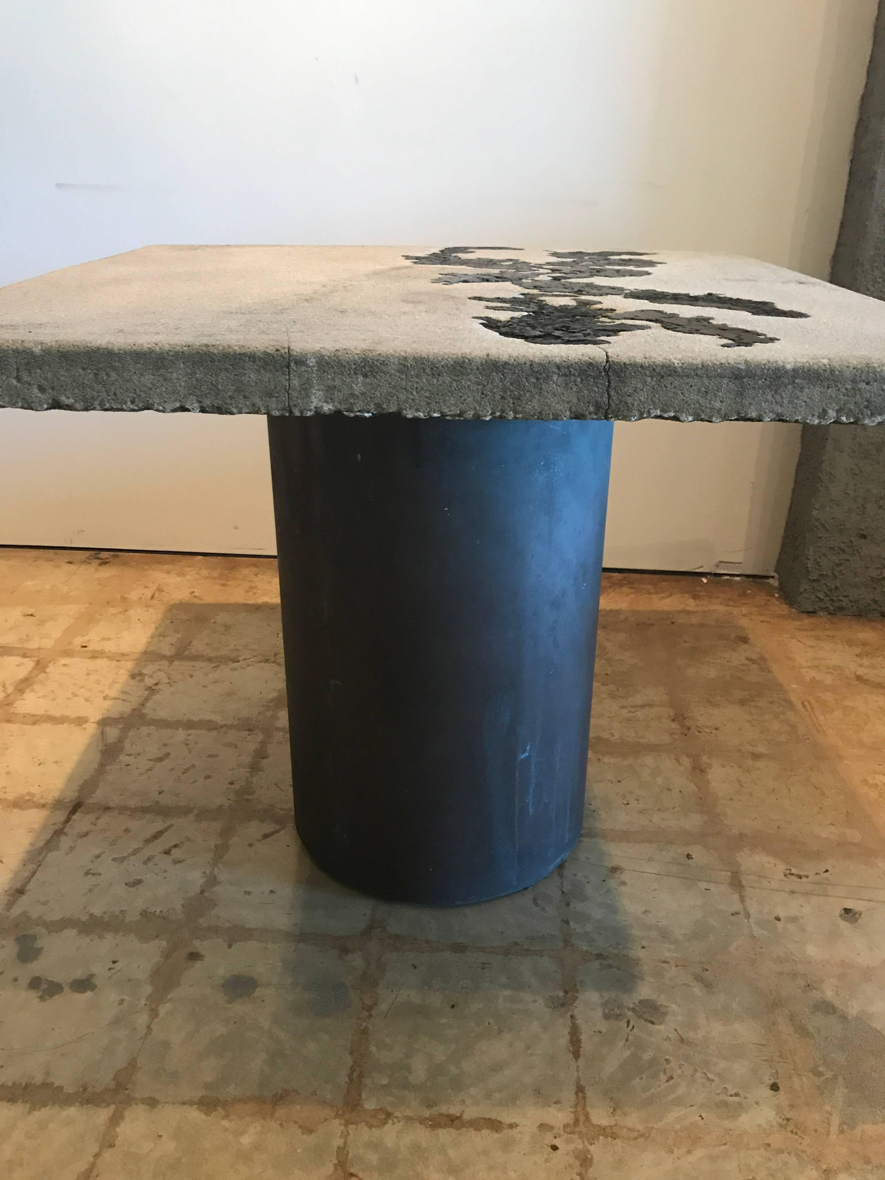 The concrete top inlaid with bronze abstract sections over a bronze cylinder base.